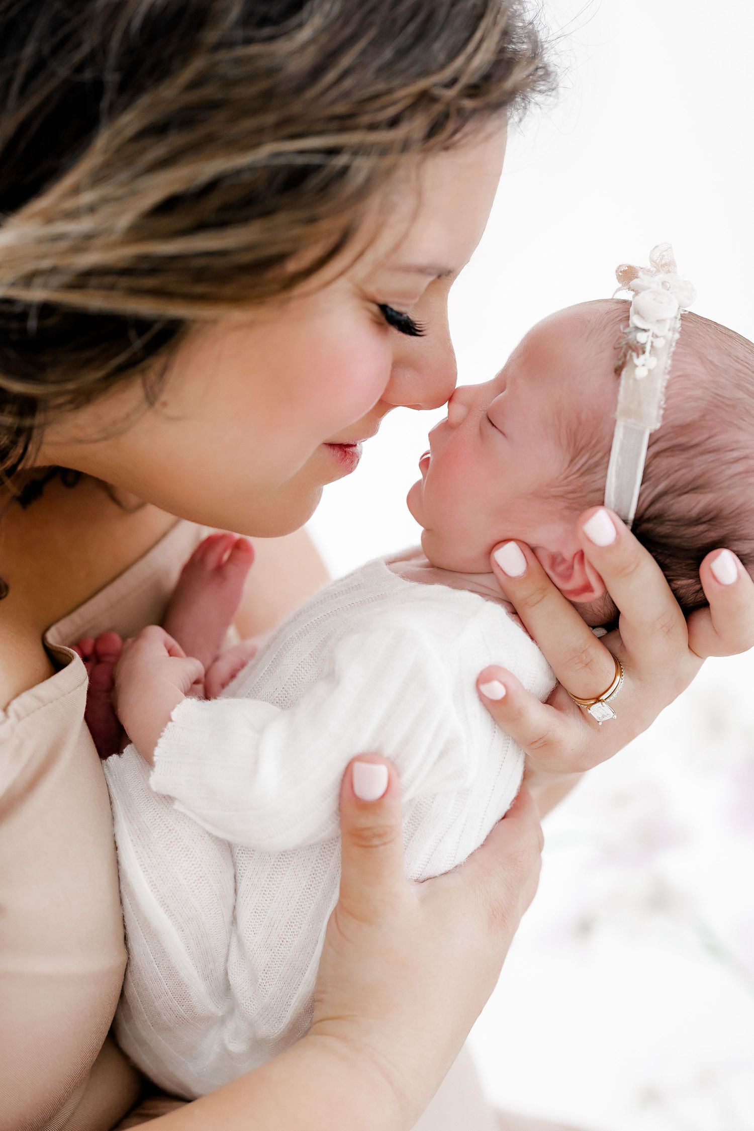 A tender moment between parent and newborn baby in white, shown in a series of close-up photos.