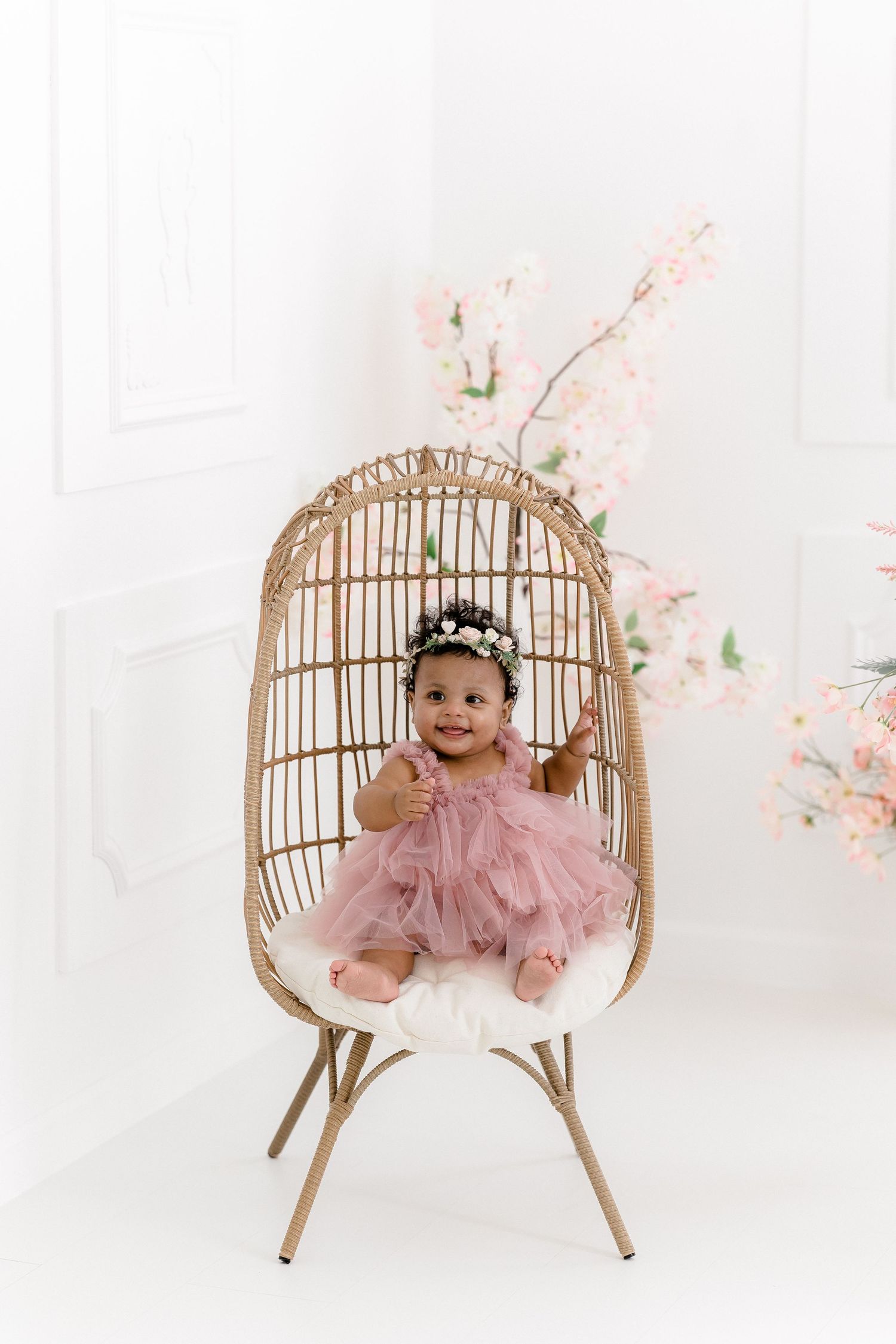 Charming portrait setup with rattan chair and pink cherry blossom decorations.