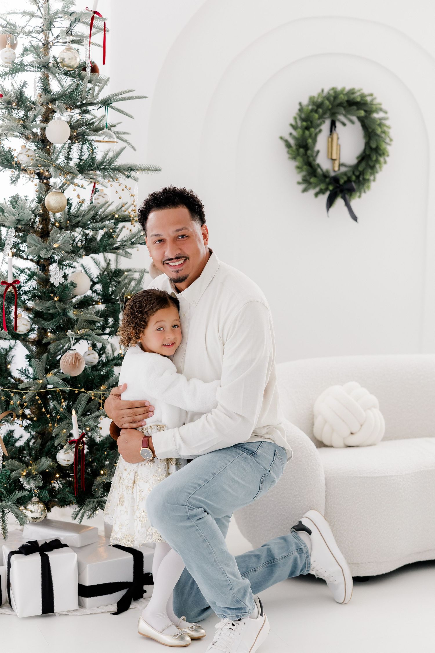 Casual holiday photos captured in a bright white studio with decorated Christmas tree.