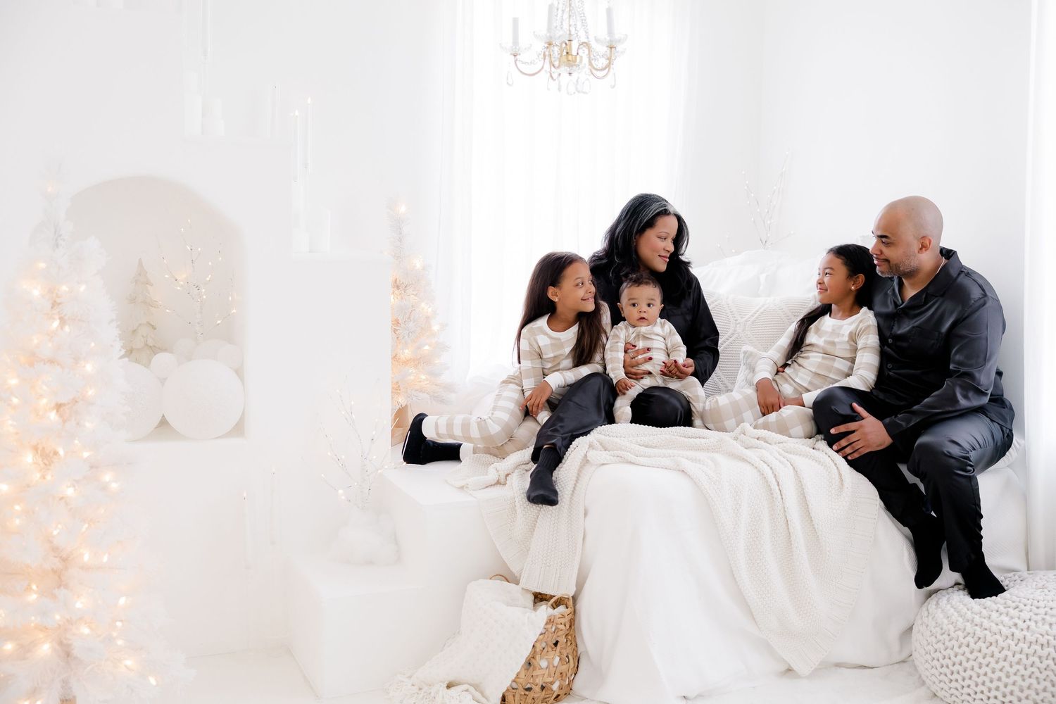 A family gathers on a white bed while enjoying holiday moments together.
