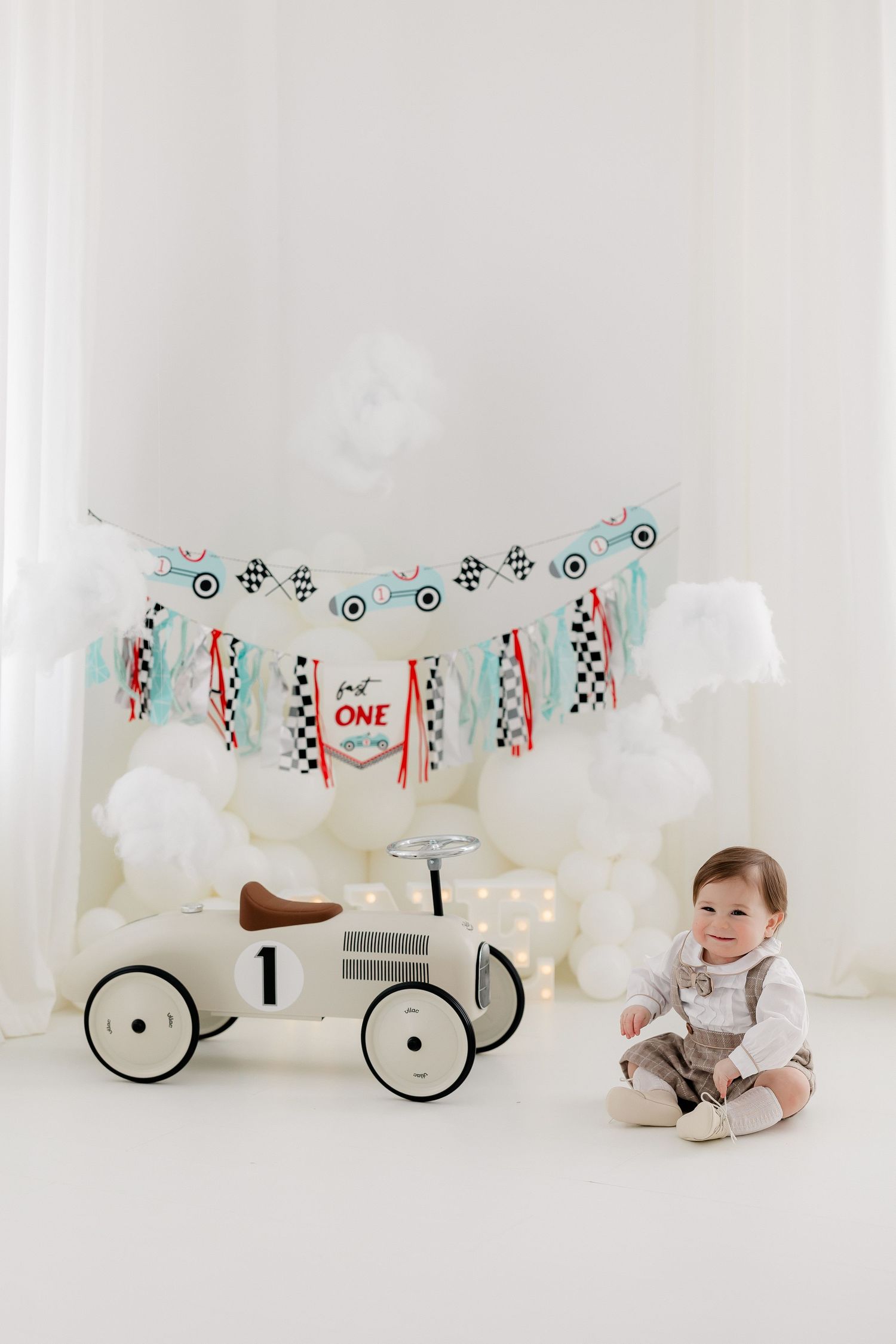 Vintage-inspired racing theme photoshoot with checkered flags and white balloons.