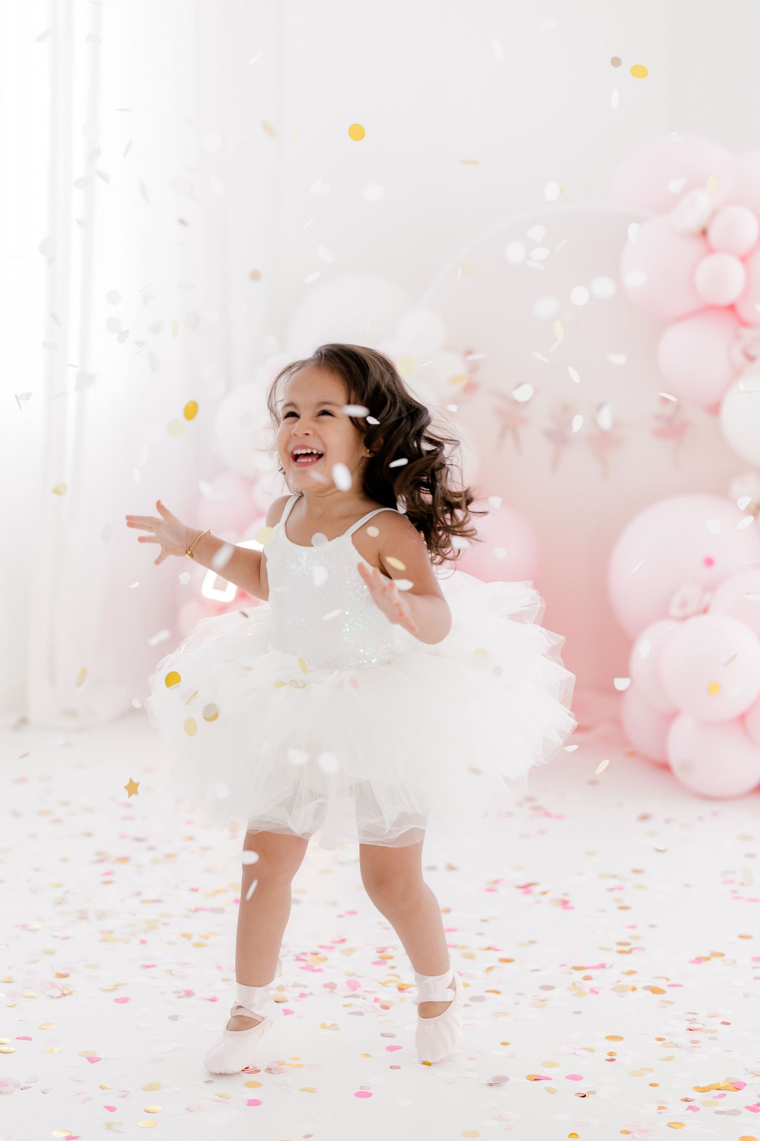 Joyful movement captured against pink balloon backdrop with floating confetti.