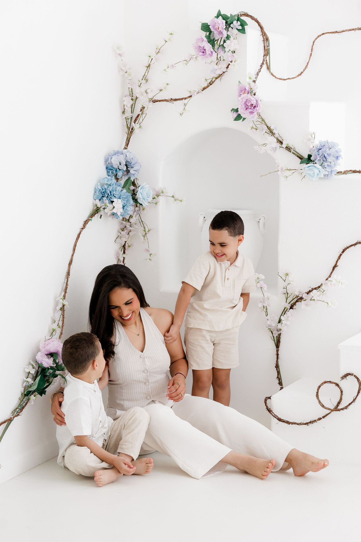 A minimalist family photoshoot series with floral decorations against a white background showing tender moments together.