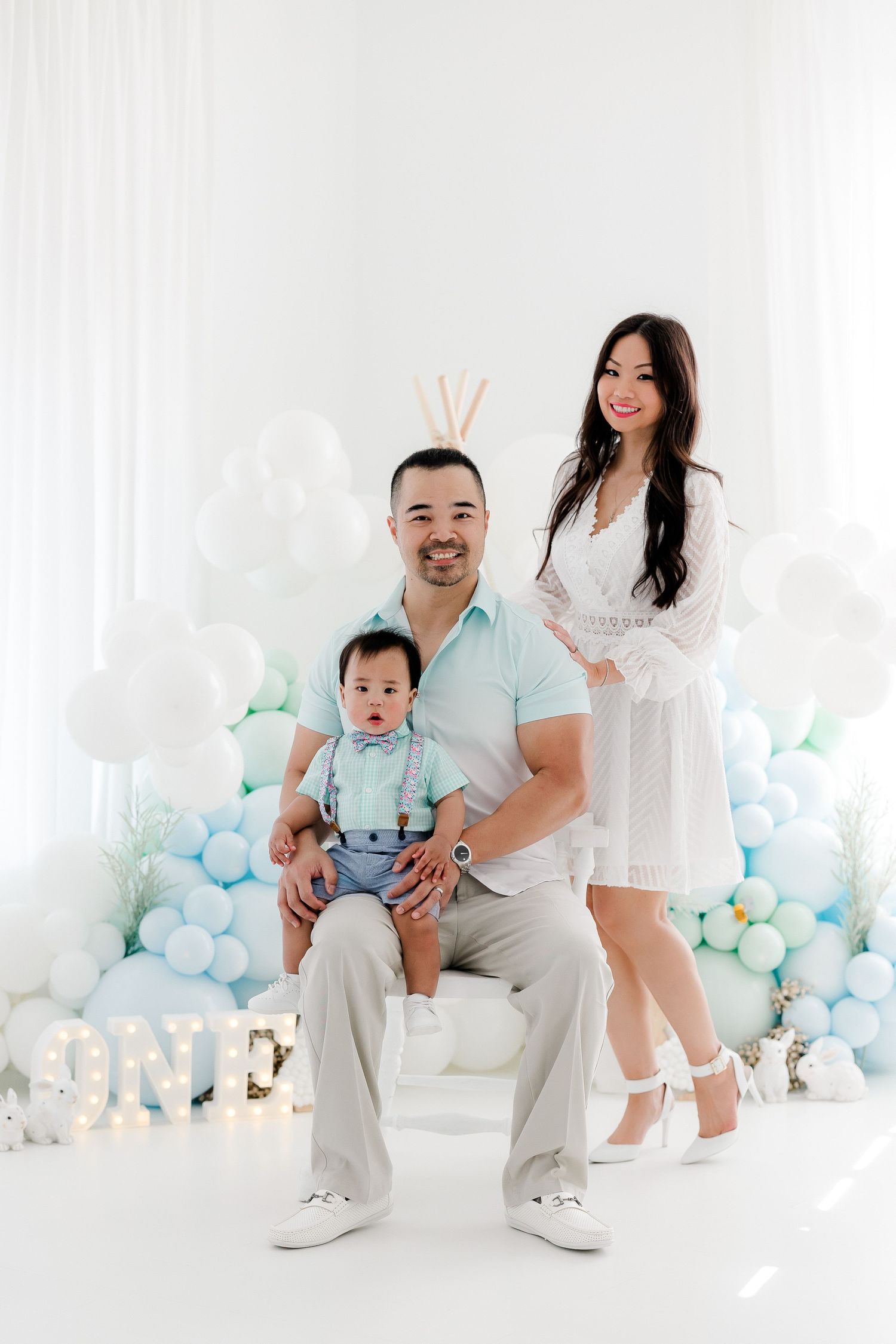 Candid family moments captured against blue and white balloon backdrop in studio.