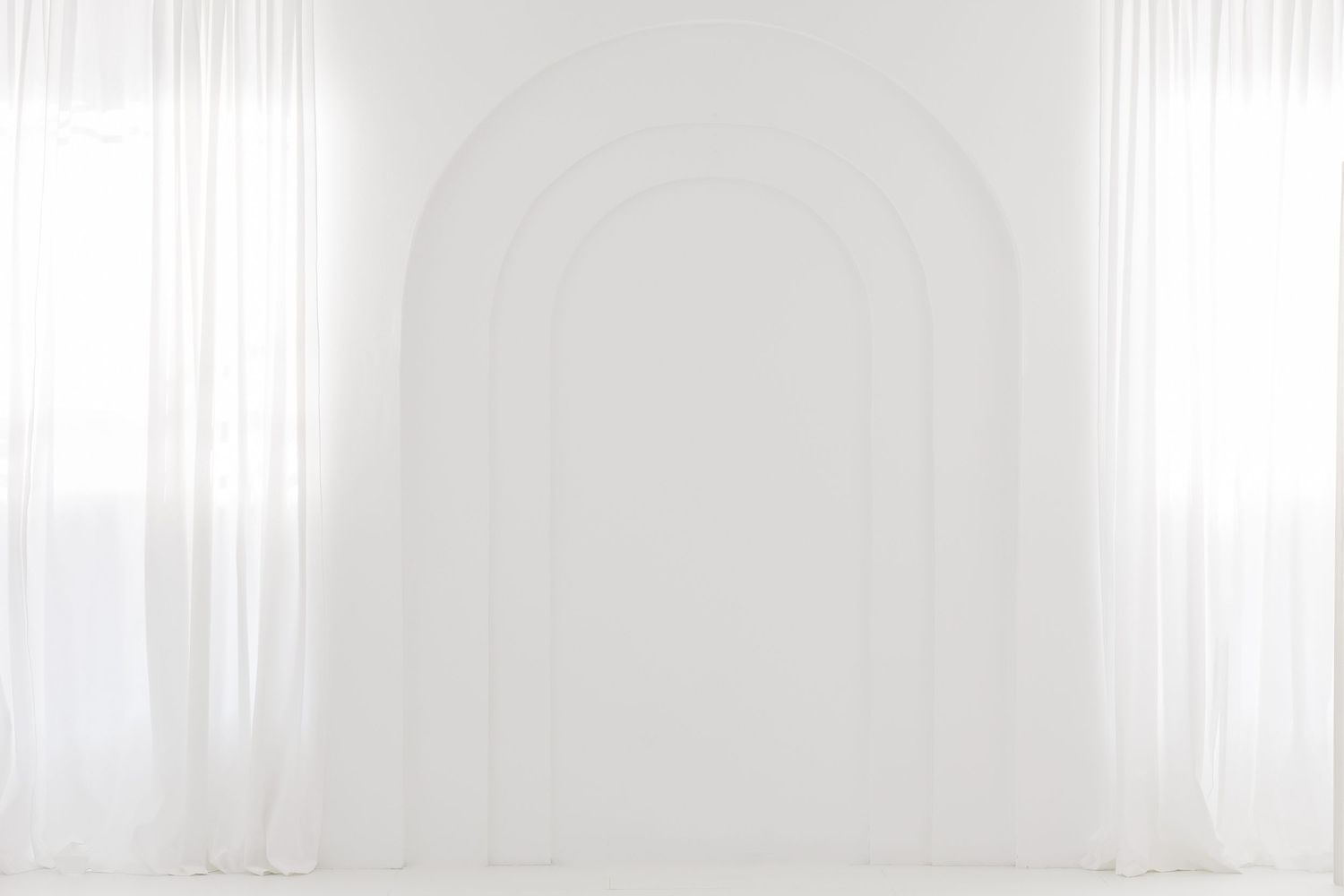 A bright white room with floor-to-ceiling sheer curtains creating a soft, ethereal atmosphere.