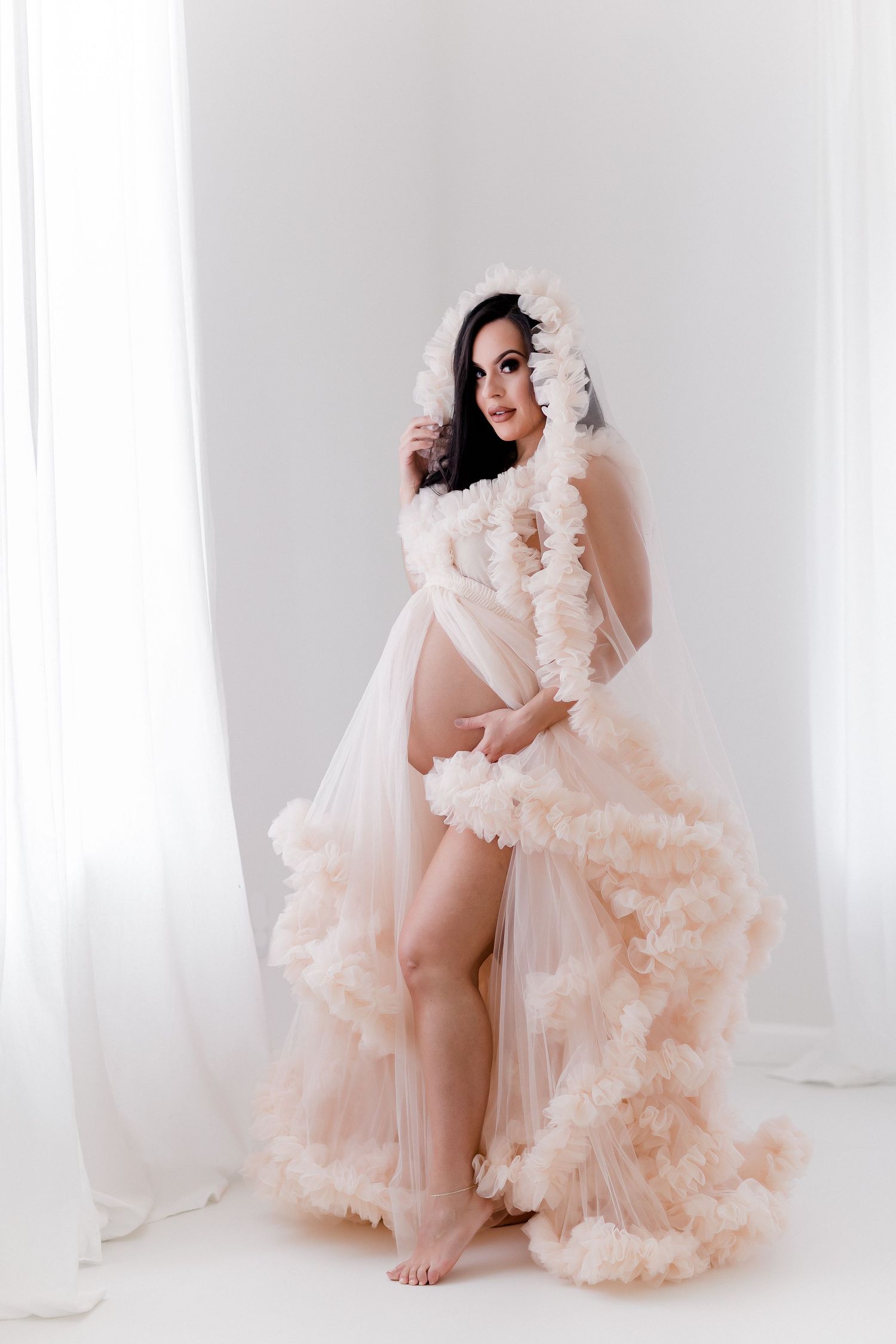 Romantic boudoir session with ruffled peach tulle gown in white studio.