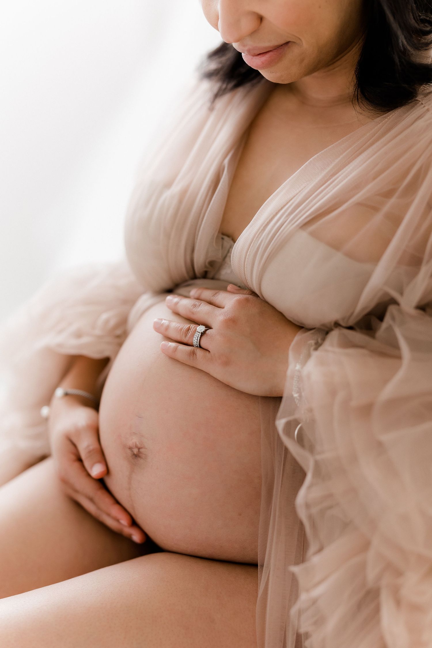 Intimate maternity photography showing close-up shots of baby bump in soft lighting.