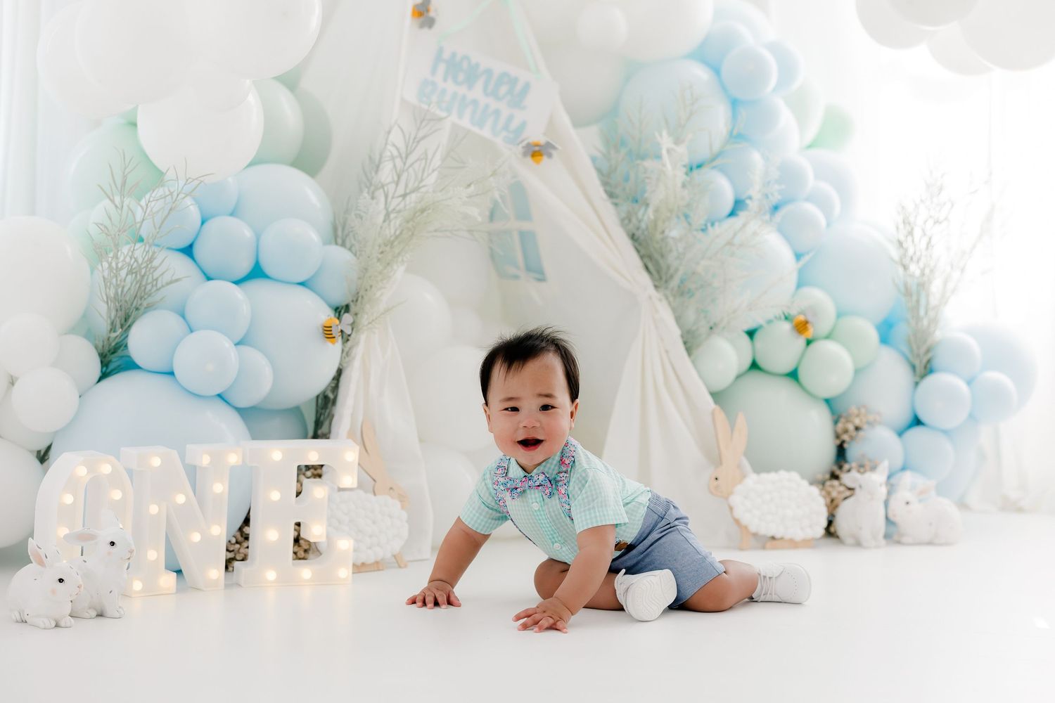 White and blue balloon arch with teepee creates magical first birthday scene.