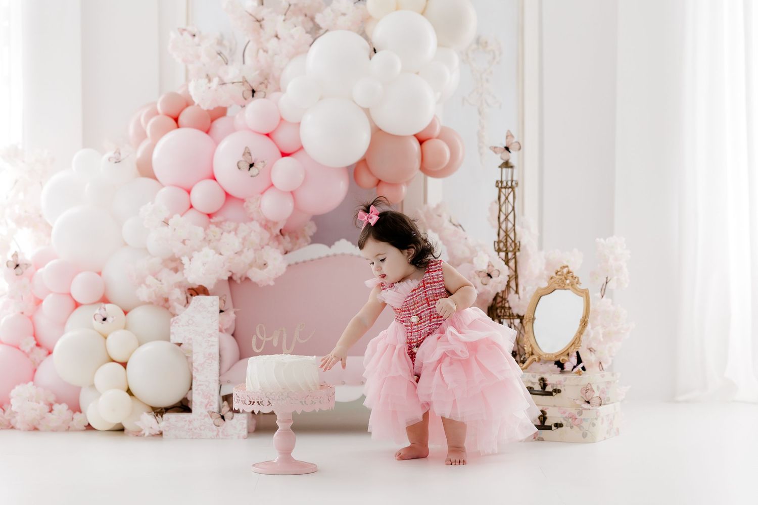 Pink and white balloon arch with elegant vintage mirror and cake stand setup.