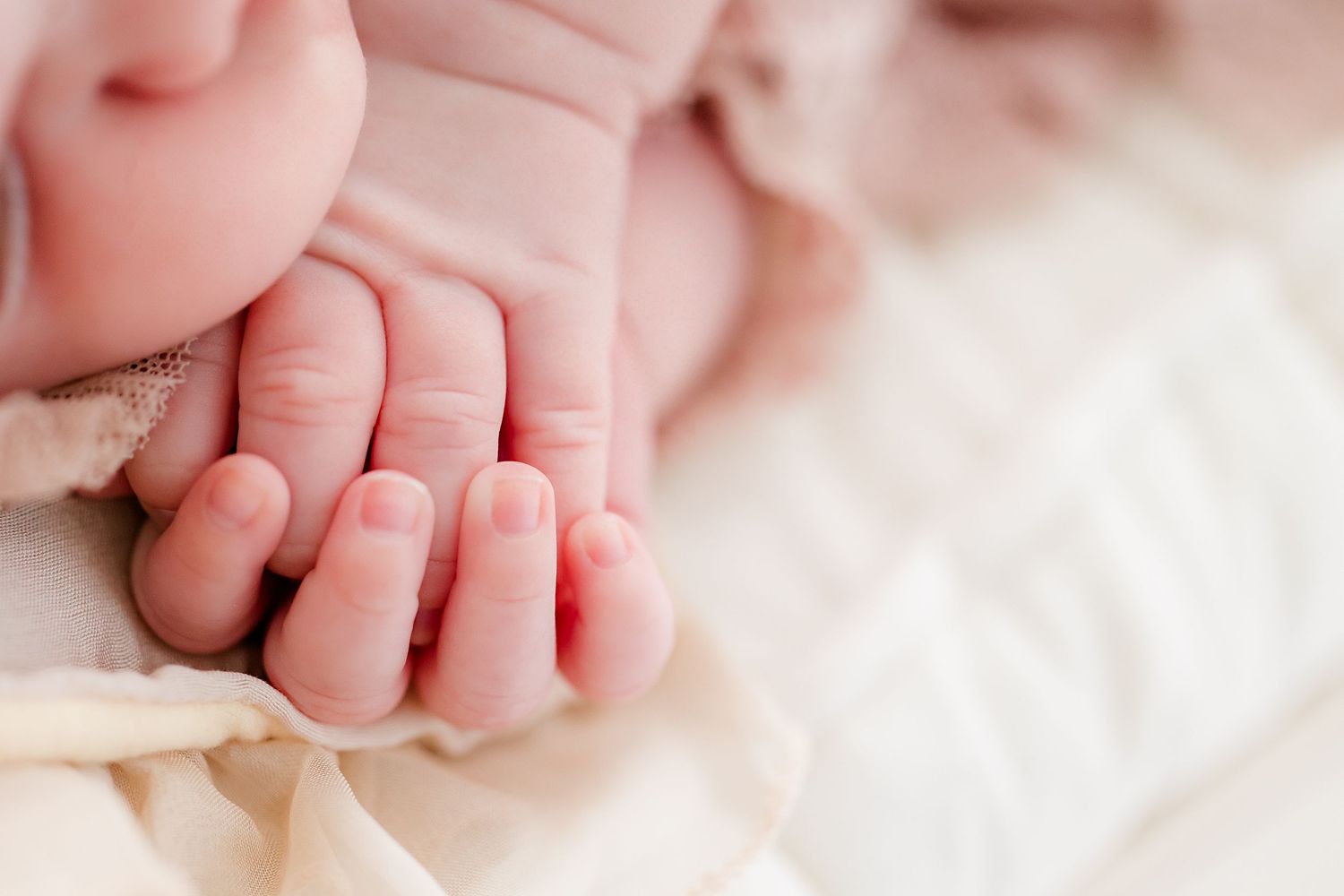 Close up of tiny baby feet and toes on white fabric.