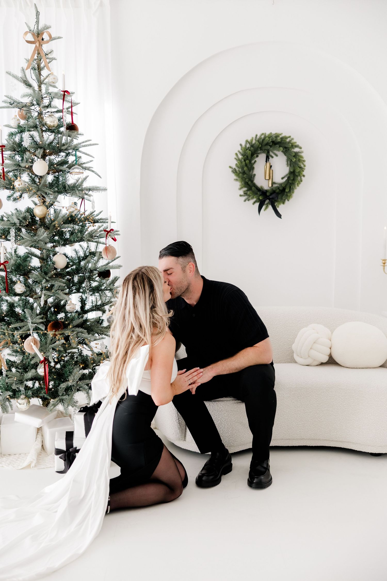 Elegant Christmas photo with decorated tree, wreath and white couch in modern minimalist setting.