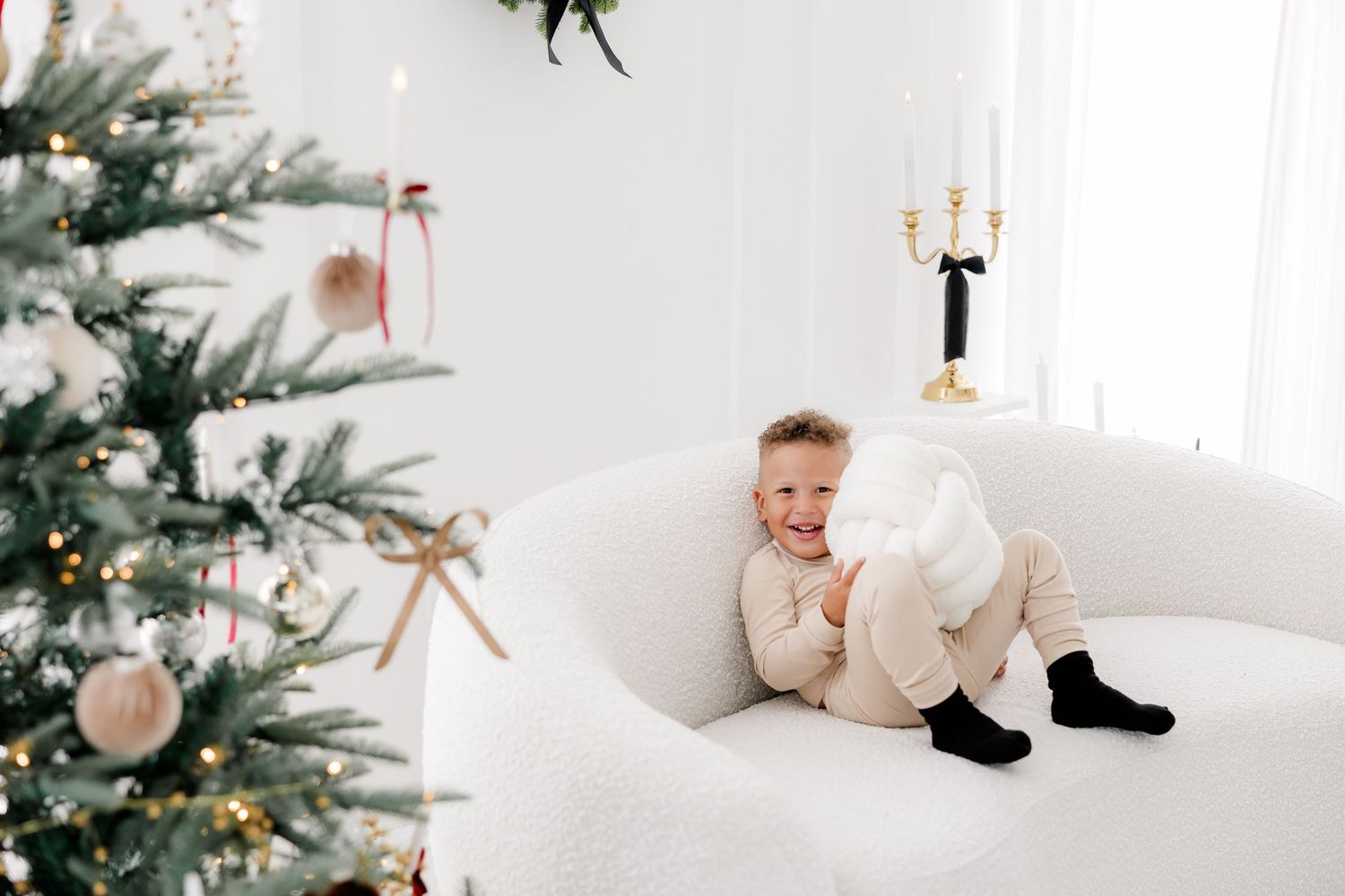 White Christmas holiday set featuring a decorated tree and gold chandelier in a bright minimal room setting.nj holiday mini sessions