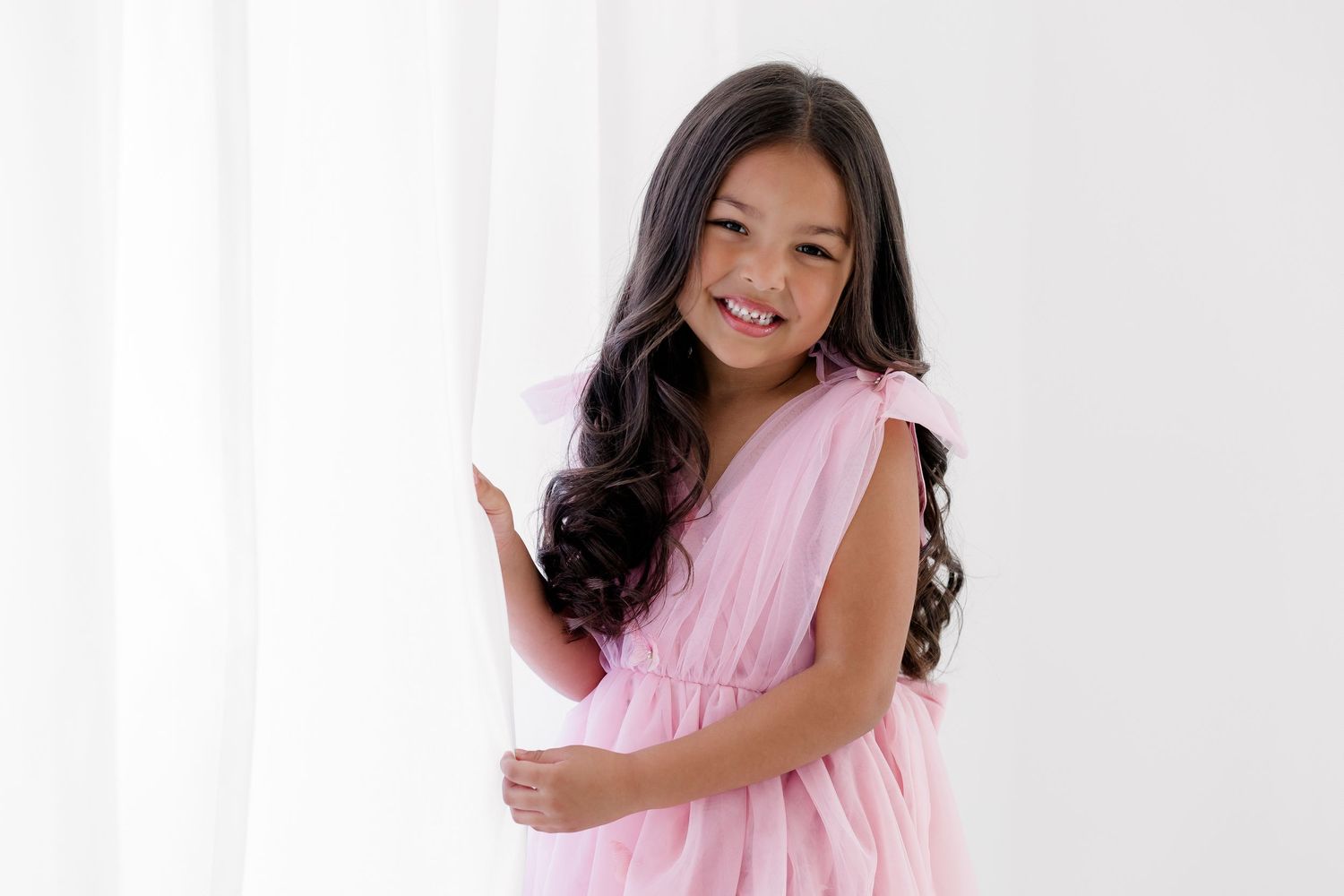 A person in a light pink dress poses against a white background in a series of connected photos.