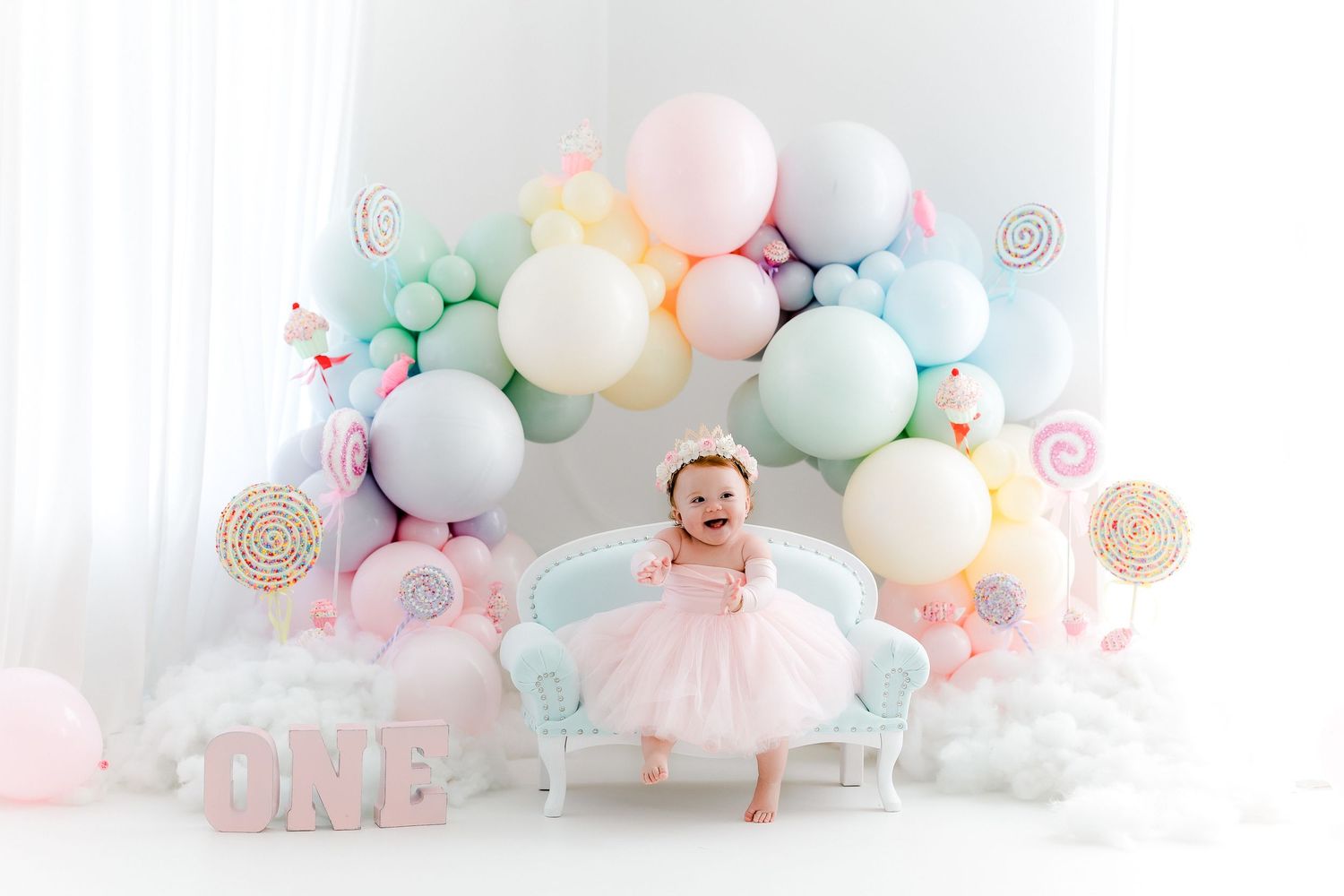 A pastel balloon garland arch with soft pink, mint, and white colors creates a dreamy party decoration setup.