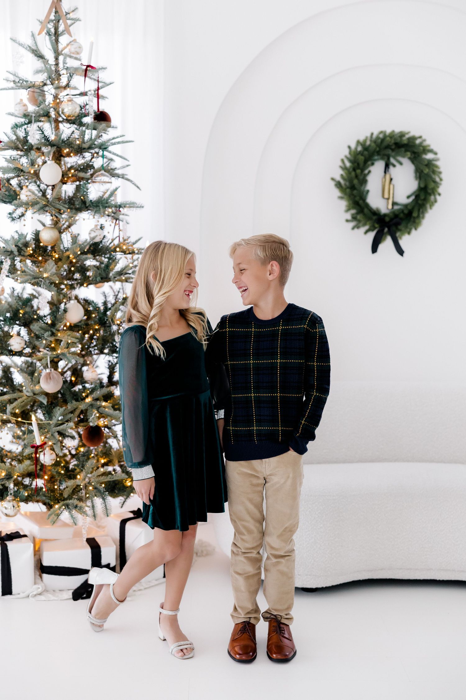 Holiday portrait of two people in coordinating outfits by decorated Christmas tree.