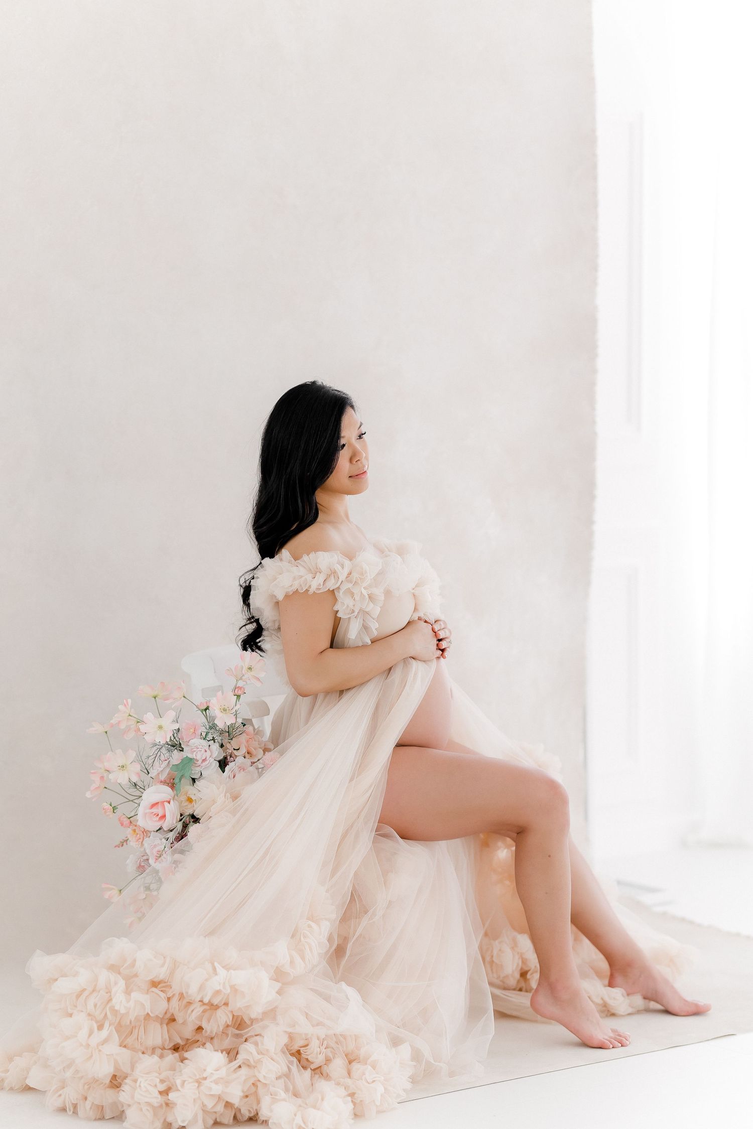 Ethereal maternity session with flowing peach dress and floral arrangements.