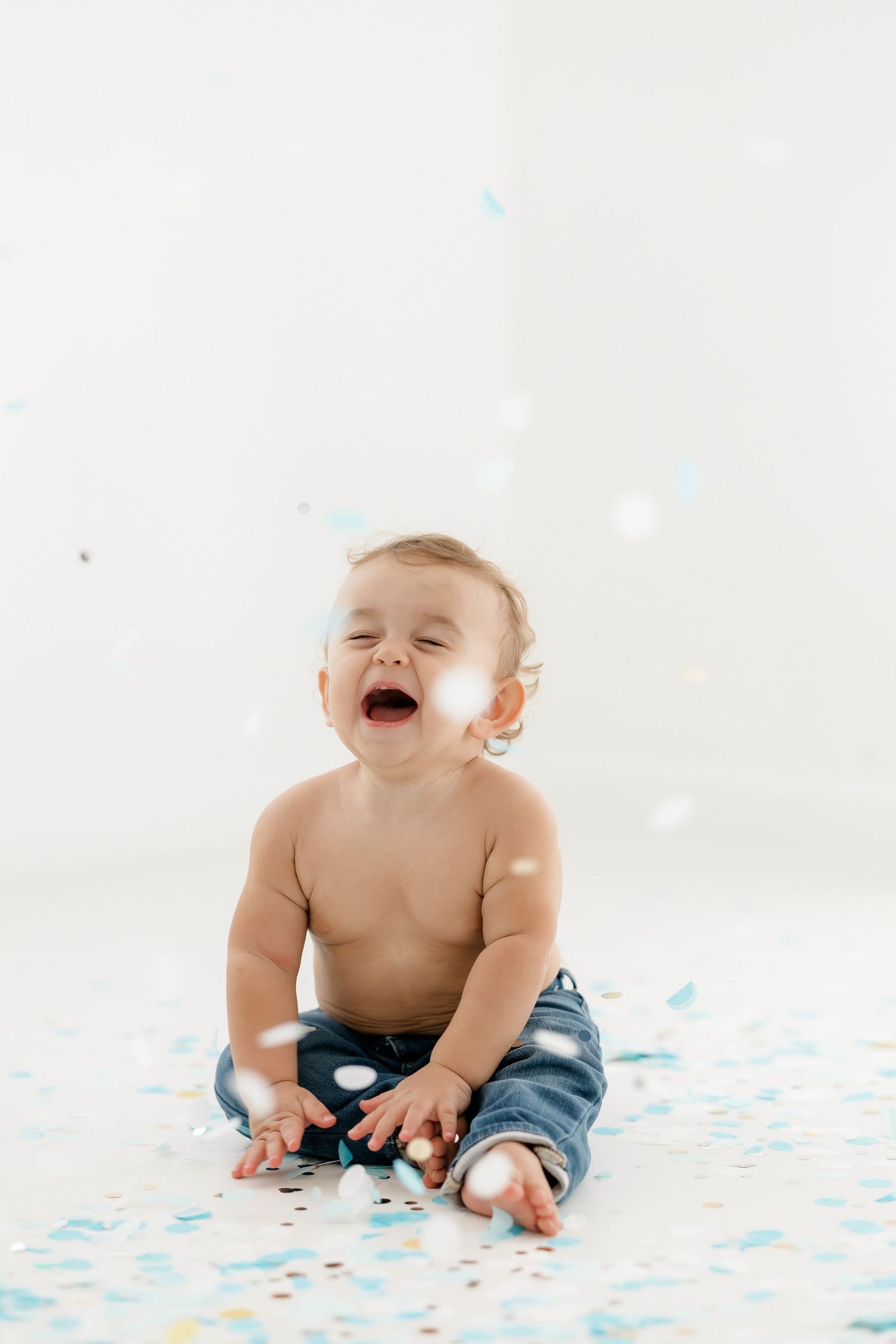 Baby in denim pants laughs and plays on polka dot blanket in three sequential photos.
