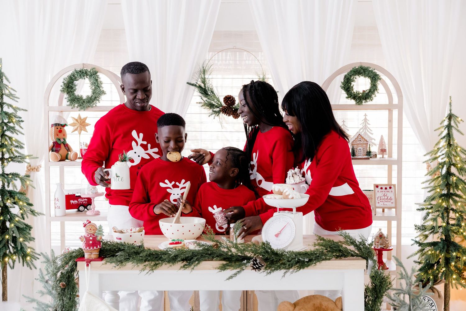 Happy family enjoys Christmas celebration in coordinated red and white outfits.