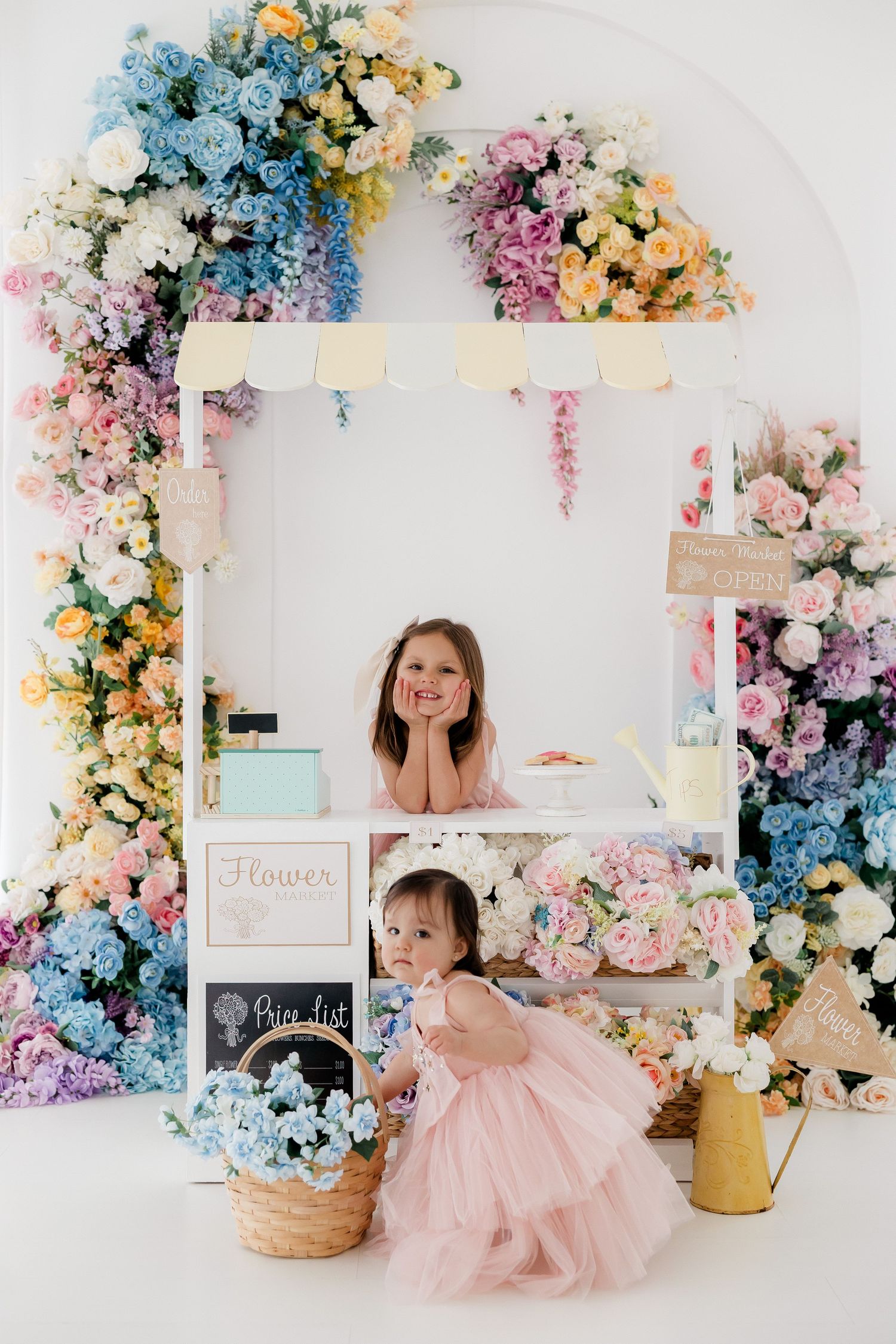 Dreamy floral photography setup with pastel flowers, white walls, and pink decor in a bright studio setting.