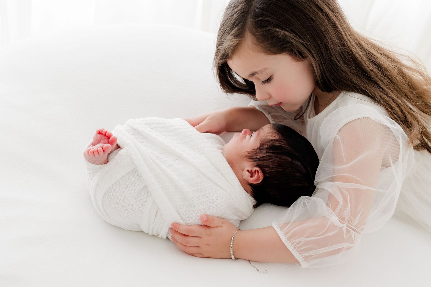 A sequence of five intimate photos shows a couple in white clothing laying together on a light background.
