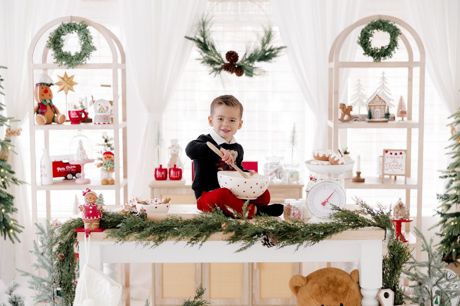 Festive white studio with Christmas decorations, wreaths, and built-in shelving displaying holiday items.