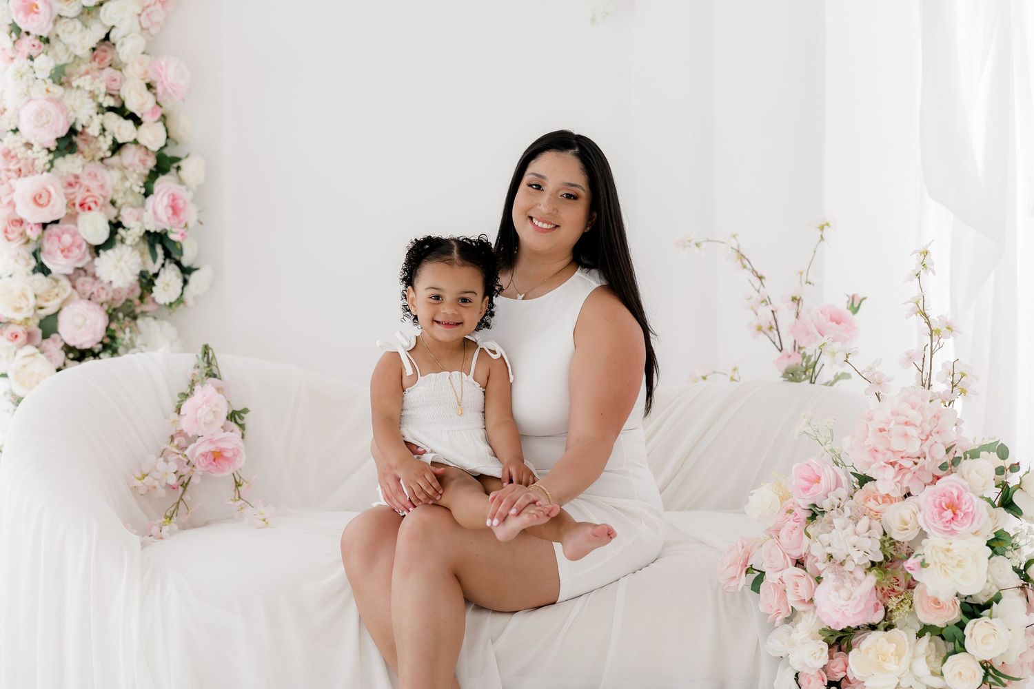 Floral backdrop with pink and white roses creates an elegant setting for a bright studio photoshoot.