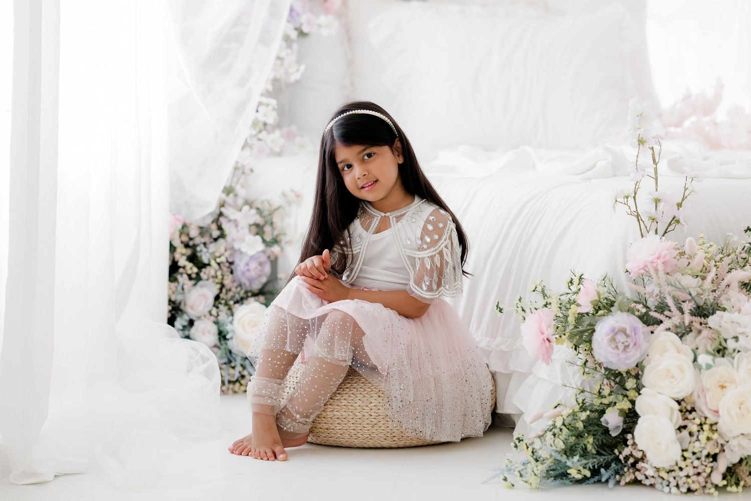 A series of soft, romantic boudoir photos featuring delicate floral arrangements and white fabric in an ethereal setting.