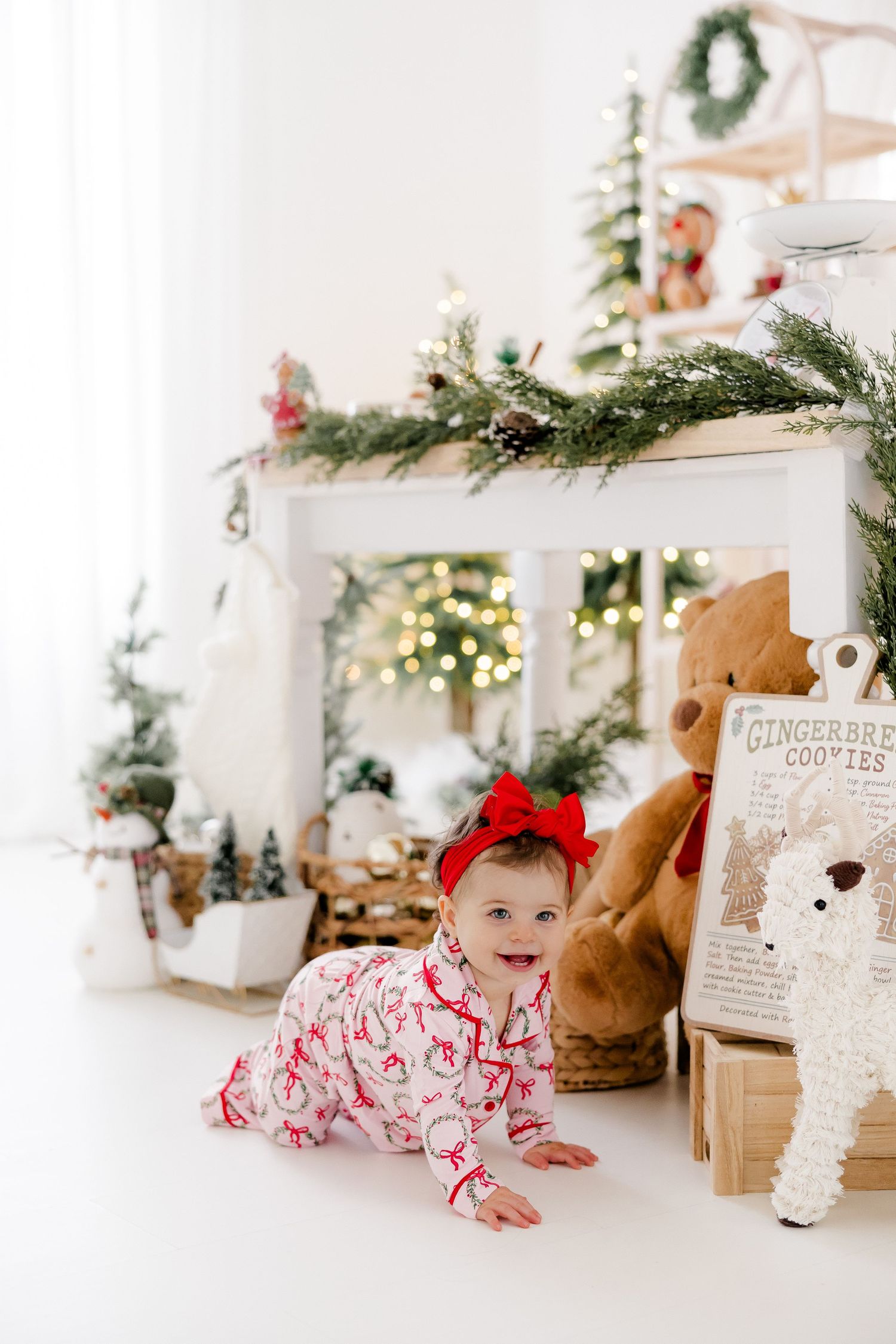 Festive holiday setup with a baby in red and white pajamas crawling near wrapped gifts and Christmas decorations.nj holiday mini sessions