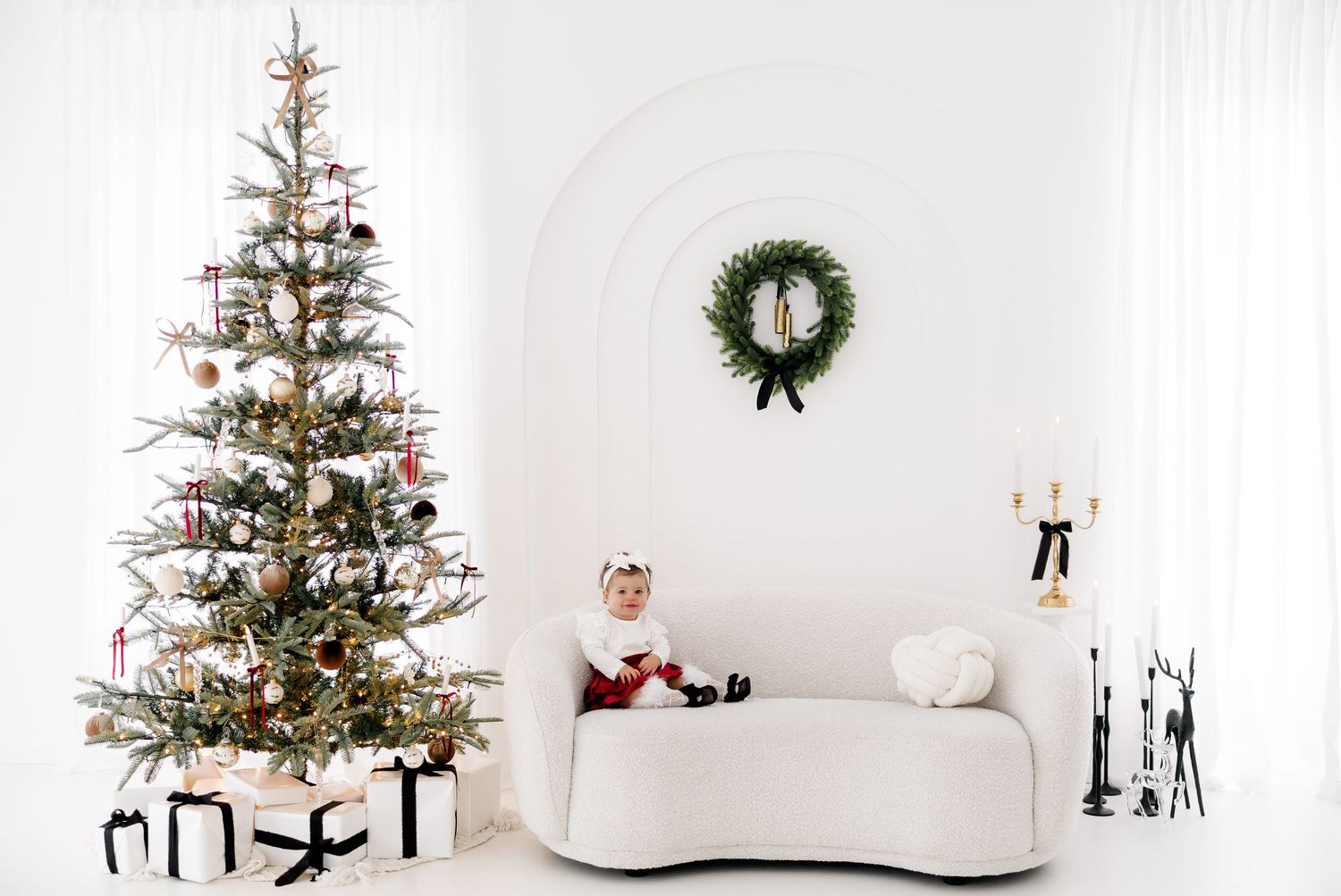 Minimalist white Christmas living room with decorated tree, wreath, and white sofa.nj holiday mini sessions