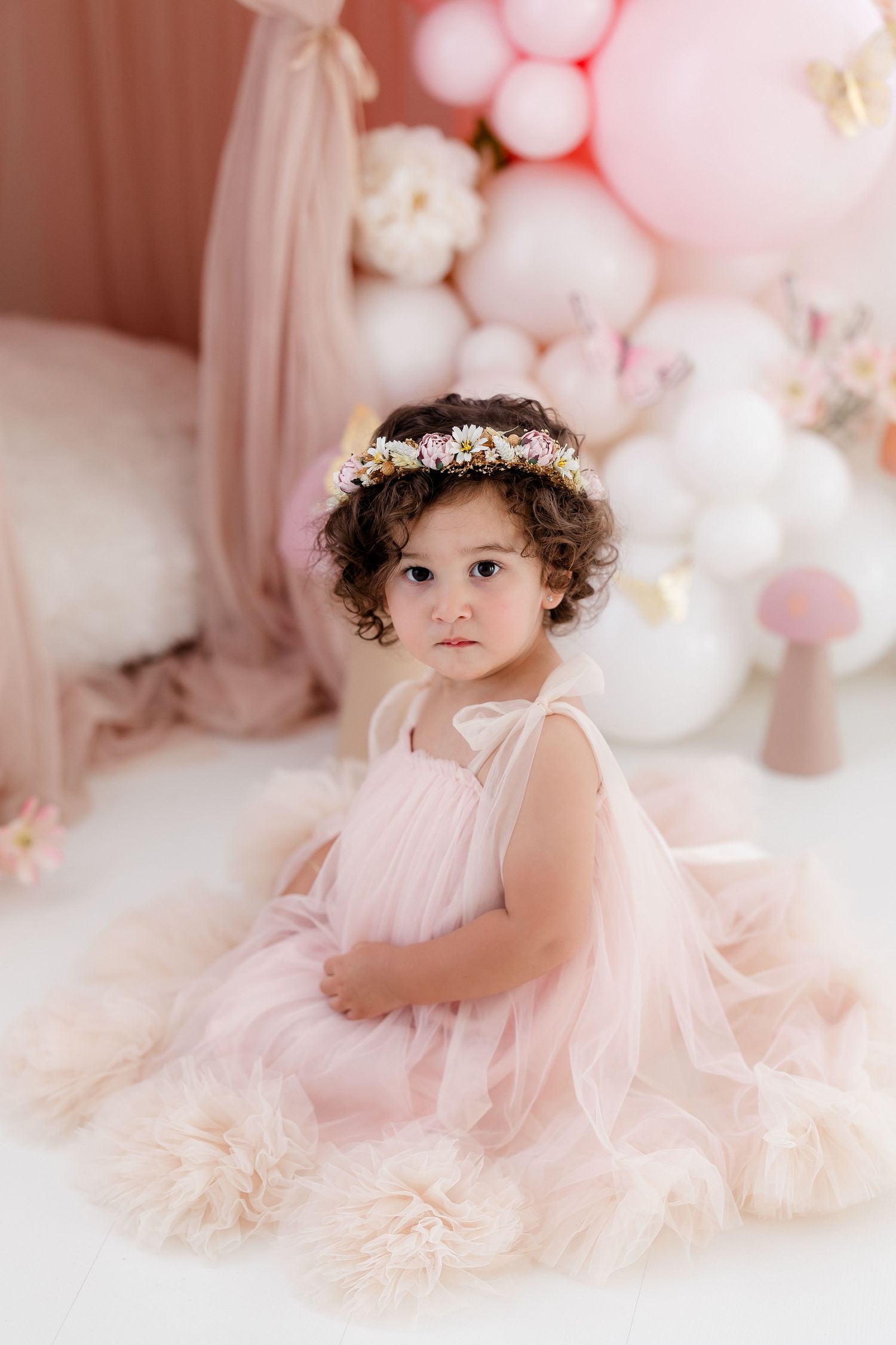 Romantic portrait session with pink balloons and soft tulle dress in pastel setting.