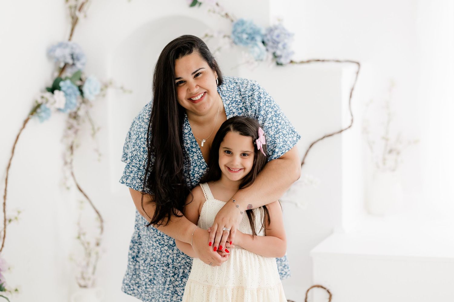A family poses together in front of a white marble background wearing coordinated blue and white outfits.
