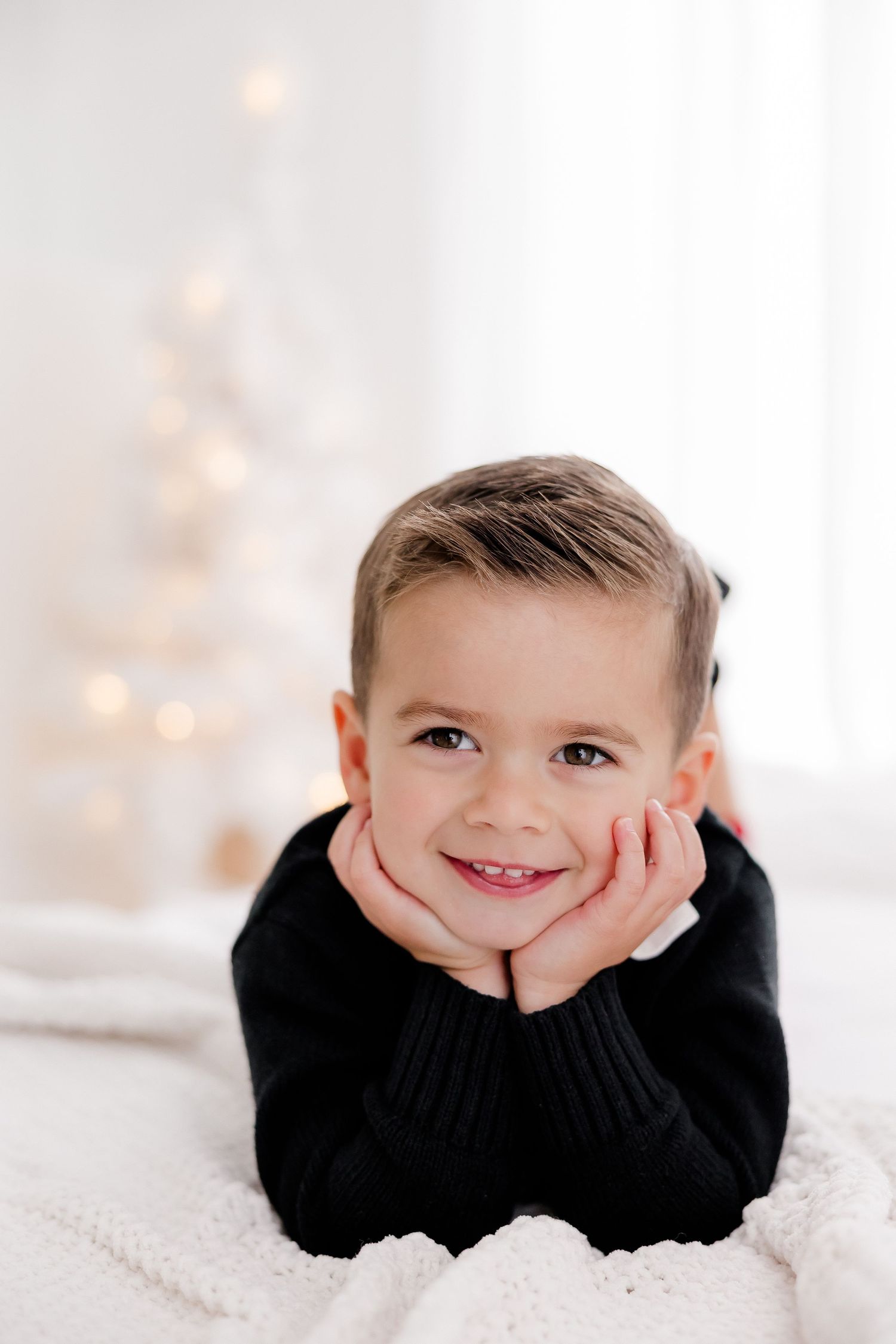 Close-up portrait on white background with joyful expression and black sweater.