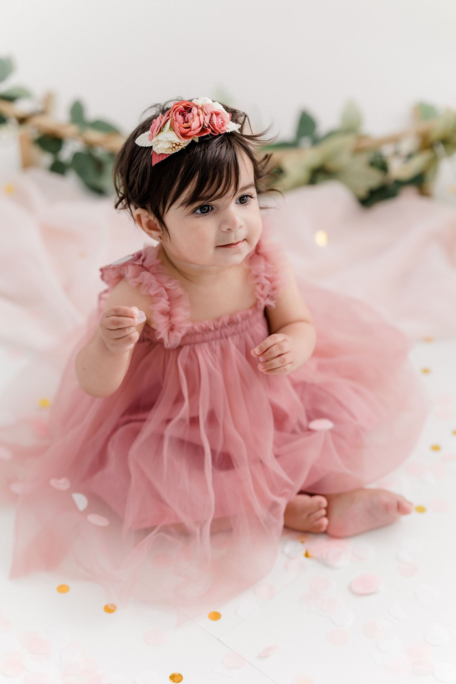 Baby girl in pink tulle dress laying on floor with floral headpiece.
