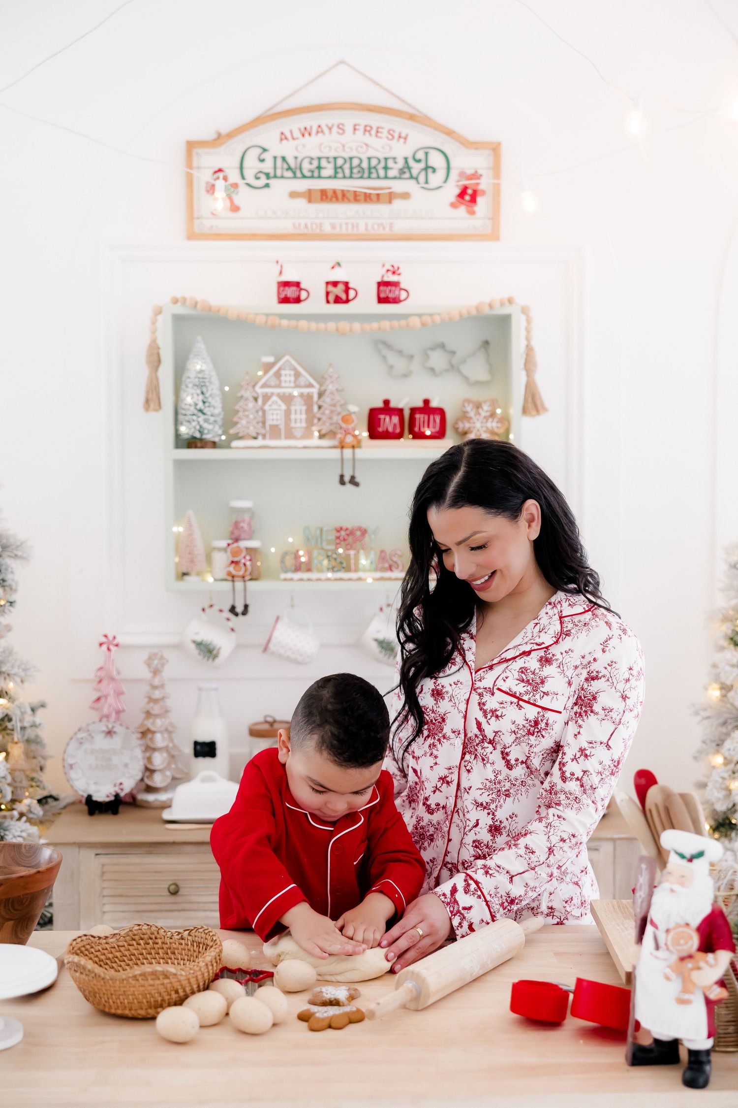 Mother and child baking Christmas cookies together in a festive holiday kitchen decorated with gingerbread signs.