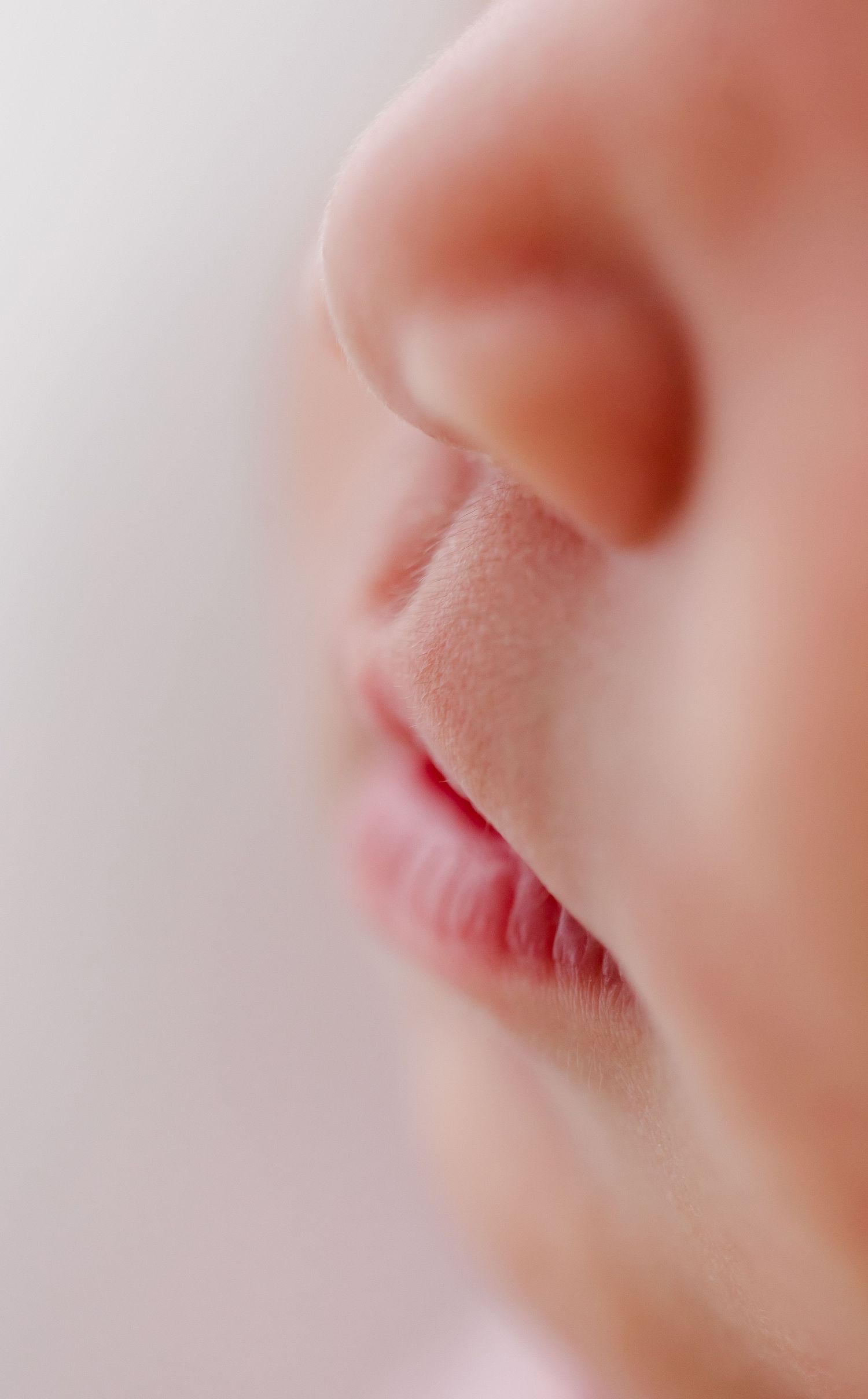 Close-up macro photo of soft pink lips with delicate skin texture in a gentle light.