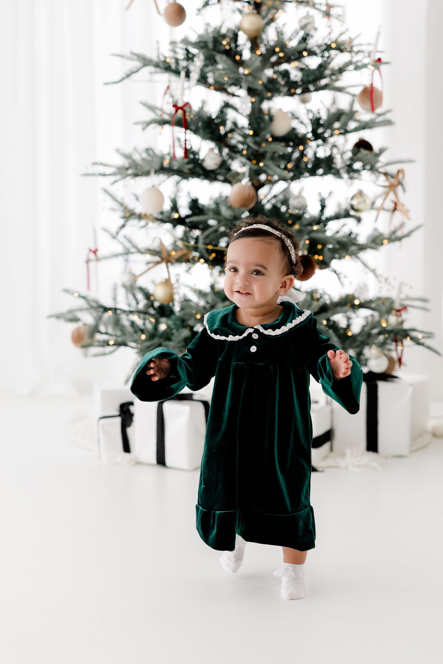 Festive holiday photo shoot with decorated Christmas tree and velvet green dress.