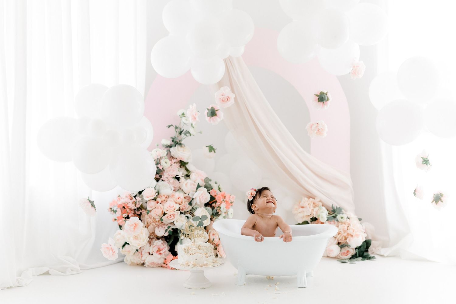 A romantic white wedding setup with pink floral arrangements and delicate drapery creating an elegant atmosphere.