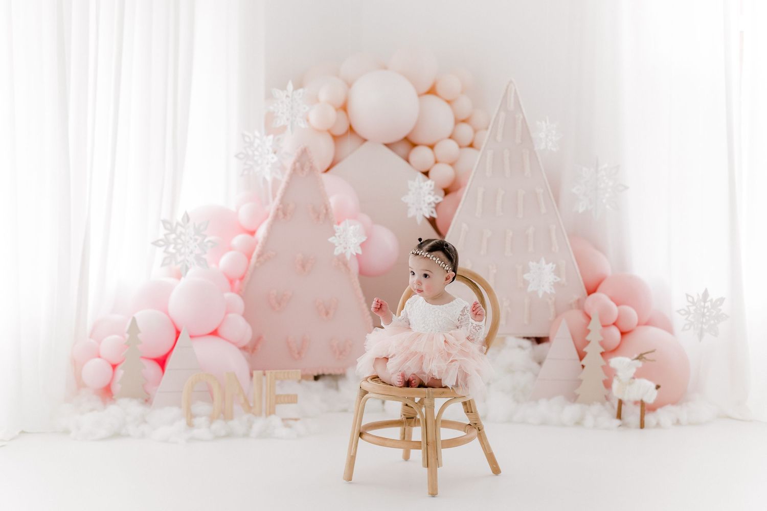 Elegant pink and white balloon arch with floral decorations creates a romantic backdrop for special occasions.