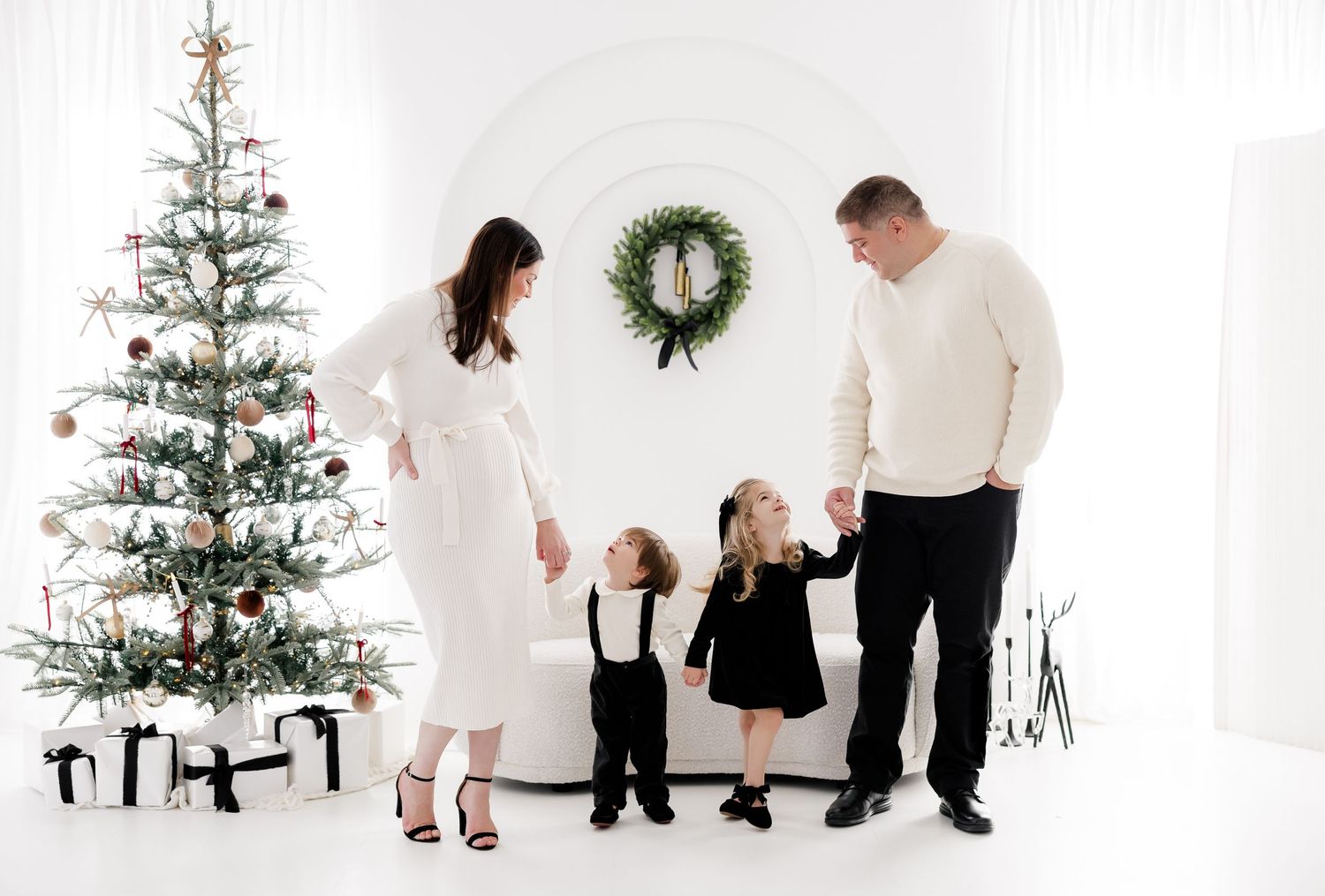 Family holiday portrait session with Christmas tree and winter white decor elements.nj holiday mini sessions