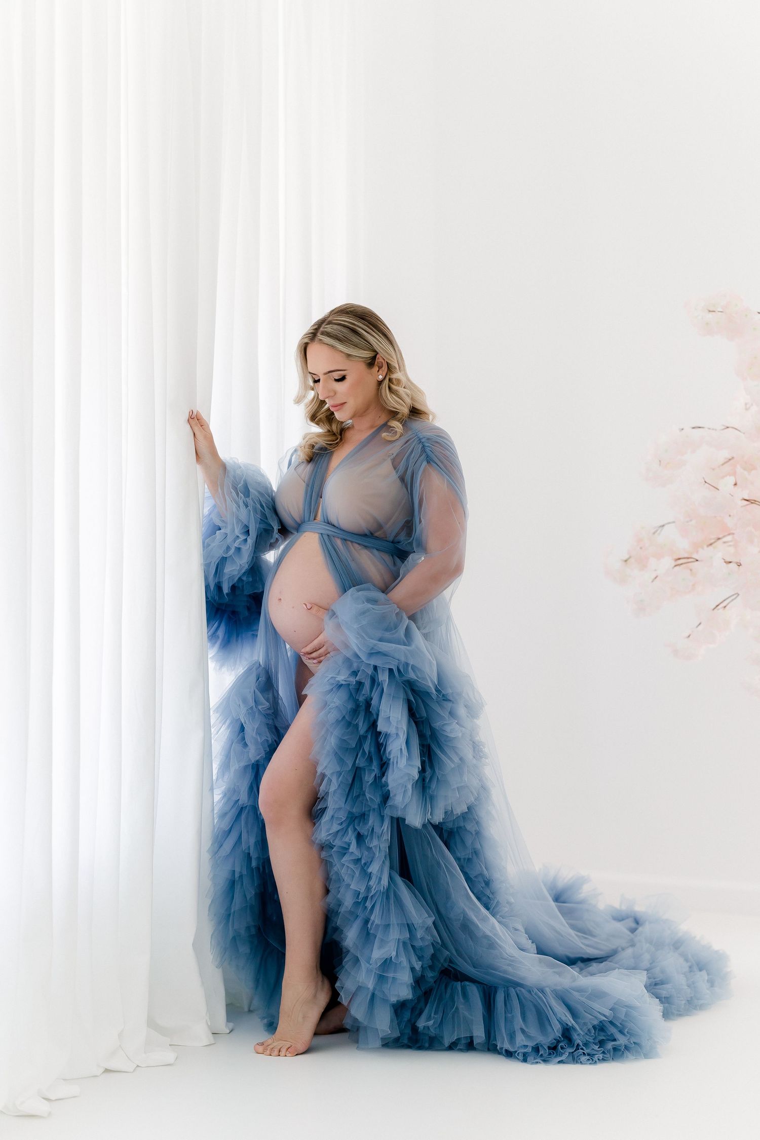 Dramatic maternity portraits in layered blue tulle gown with romantic styling.