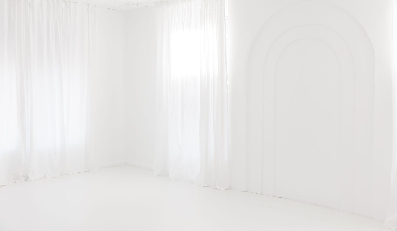 A bright white modern bathroom interior with a freestanding tub and large windows letting in natural light.