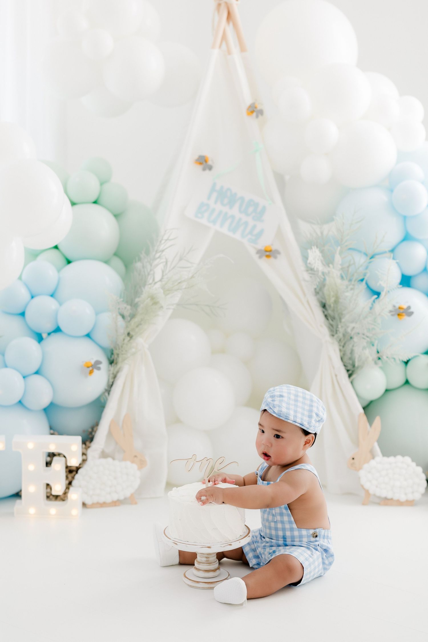 Baby's cake smash photography session with blue and white balloons and teepee decorations.