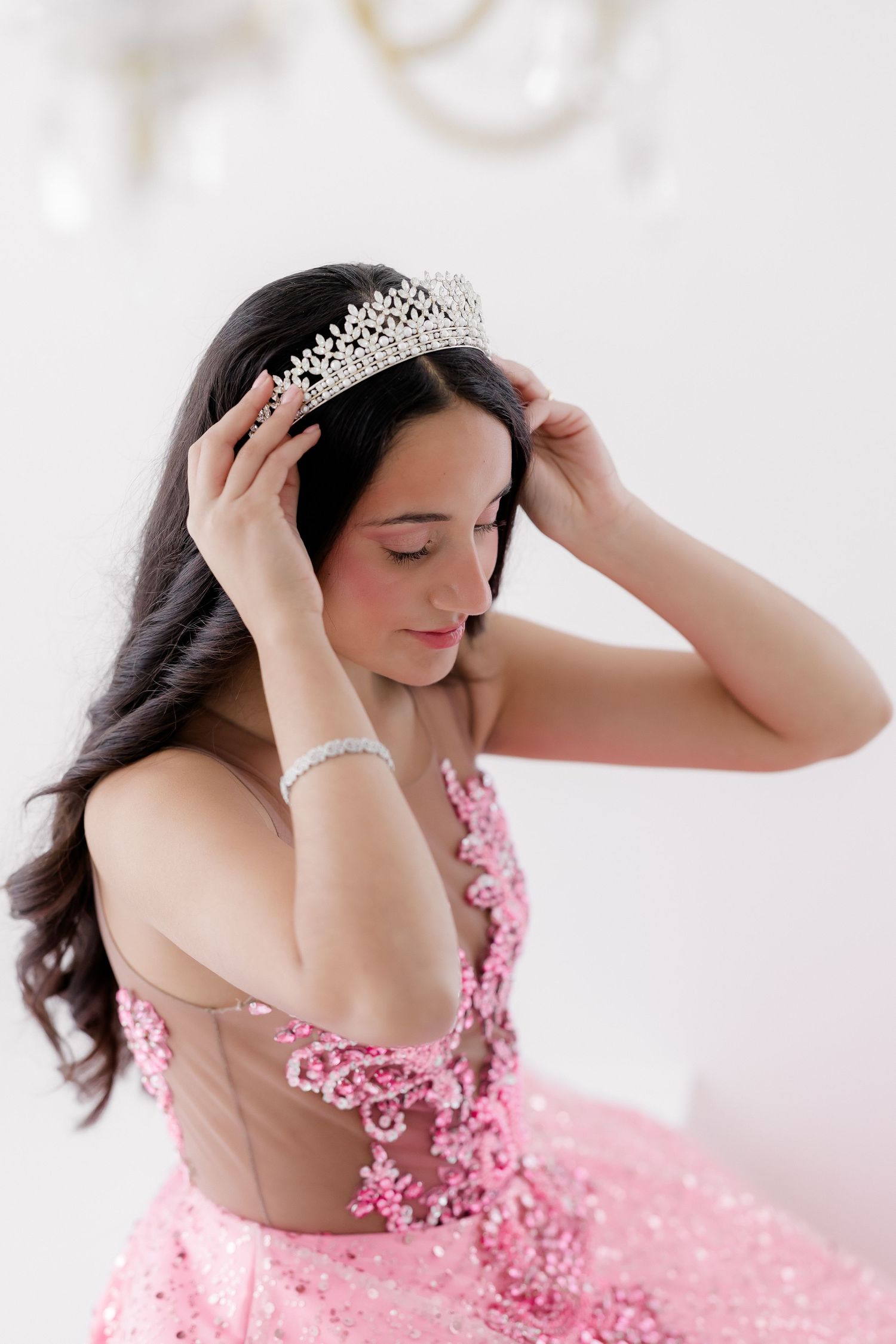 Elegant pink ballgown with floral appliques and crystal tiara crown for special occasion or quinceanera dress.
