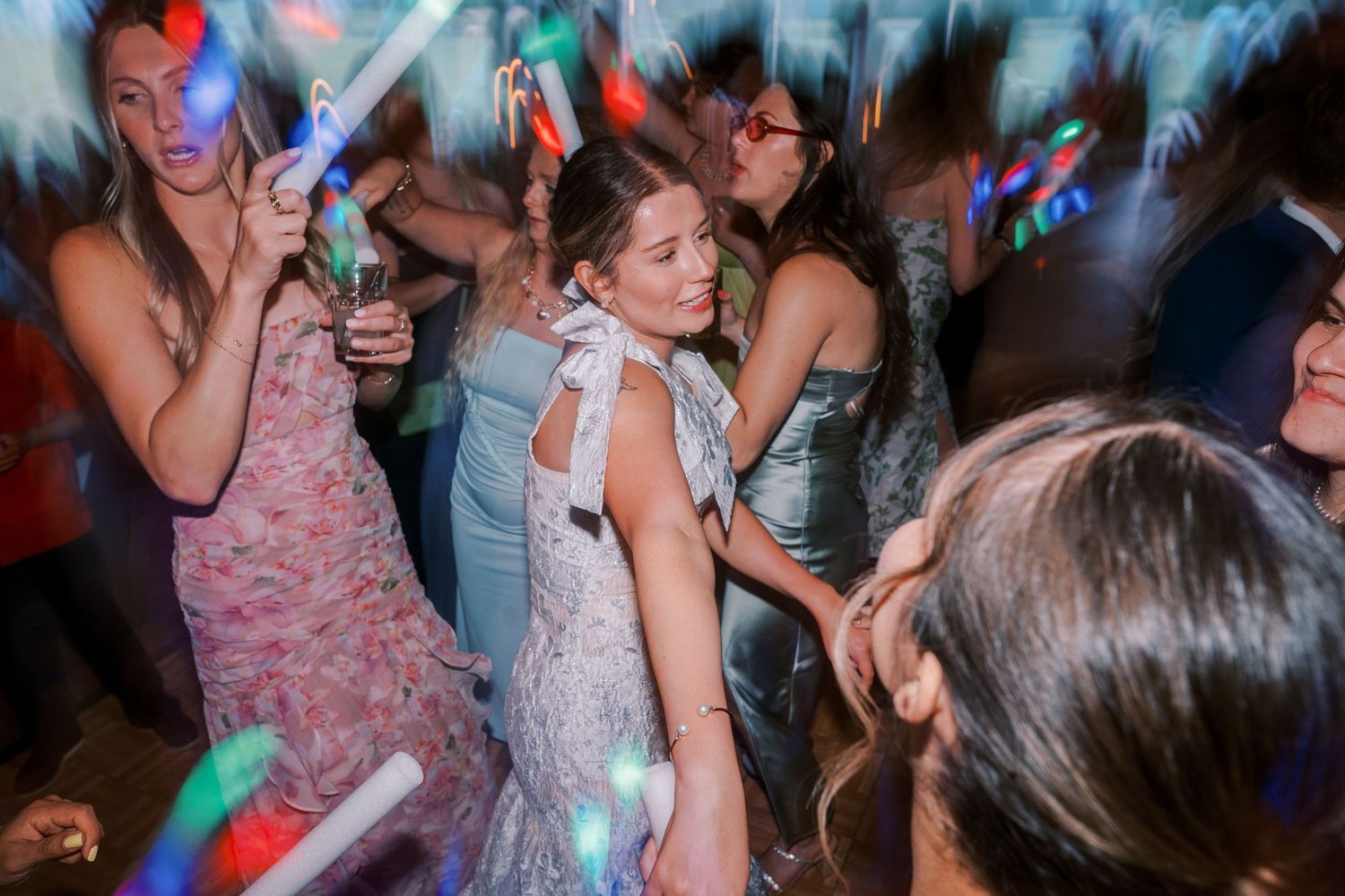 Colorful dance floor lit with bright lights and disco effects showing party goers dancing and celebrating at a nighttime event.