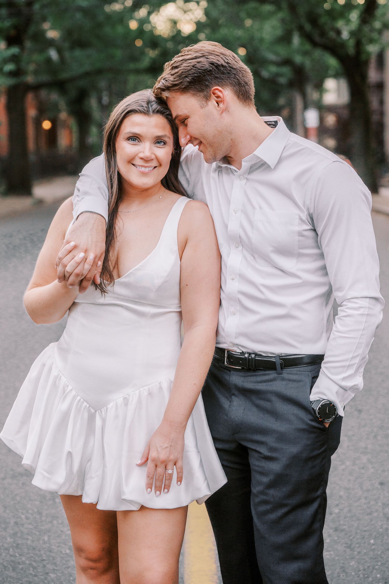 Couple posses romantically together during outdoor engagement photo session in summer.