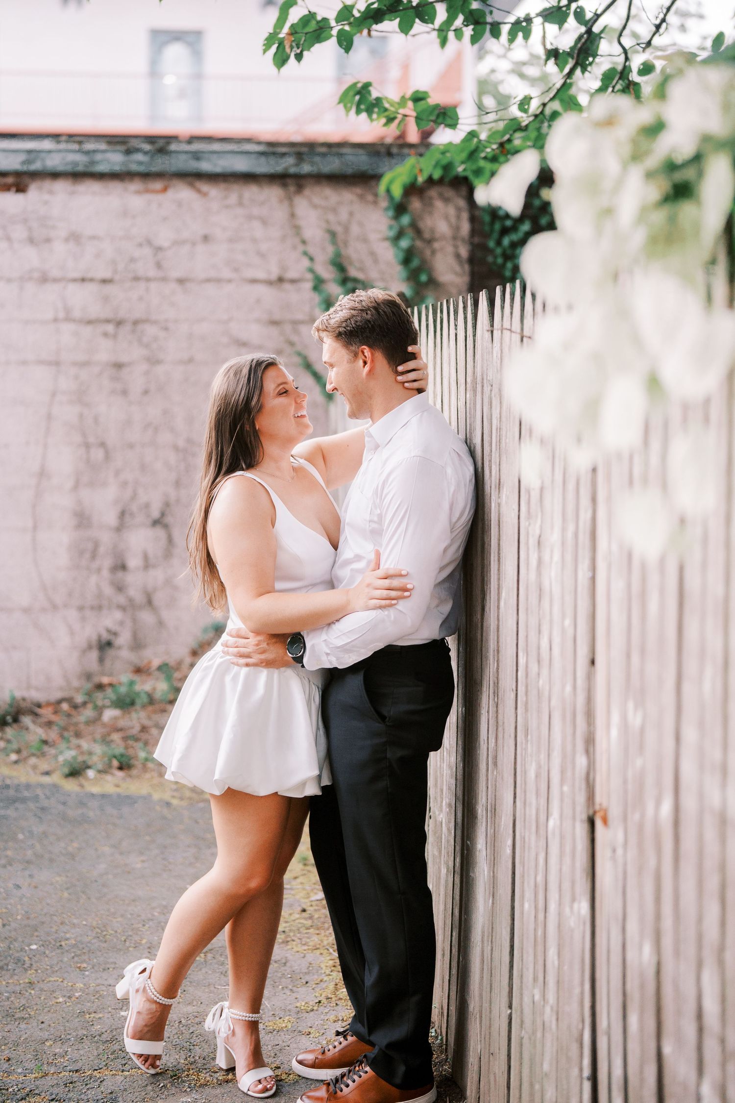 A romantic couple in formal attire share tender moments against a rustic wooden fence in a series of intimate poses.