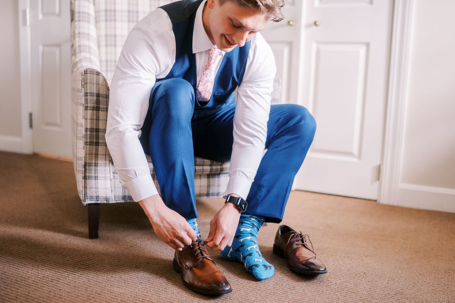 Close-up view of brown leather dress shoes being laced up on light carpet flooring.