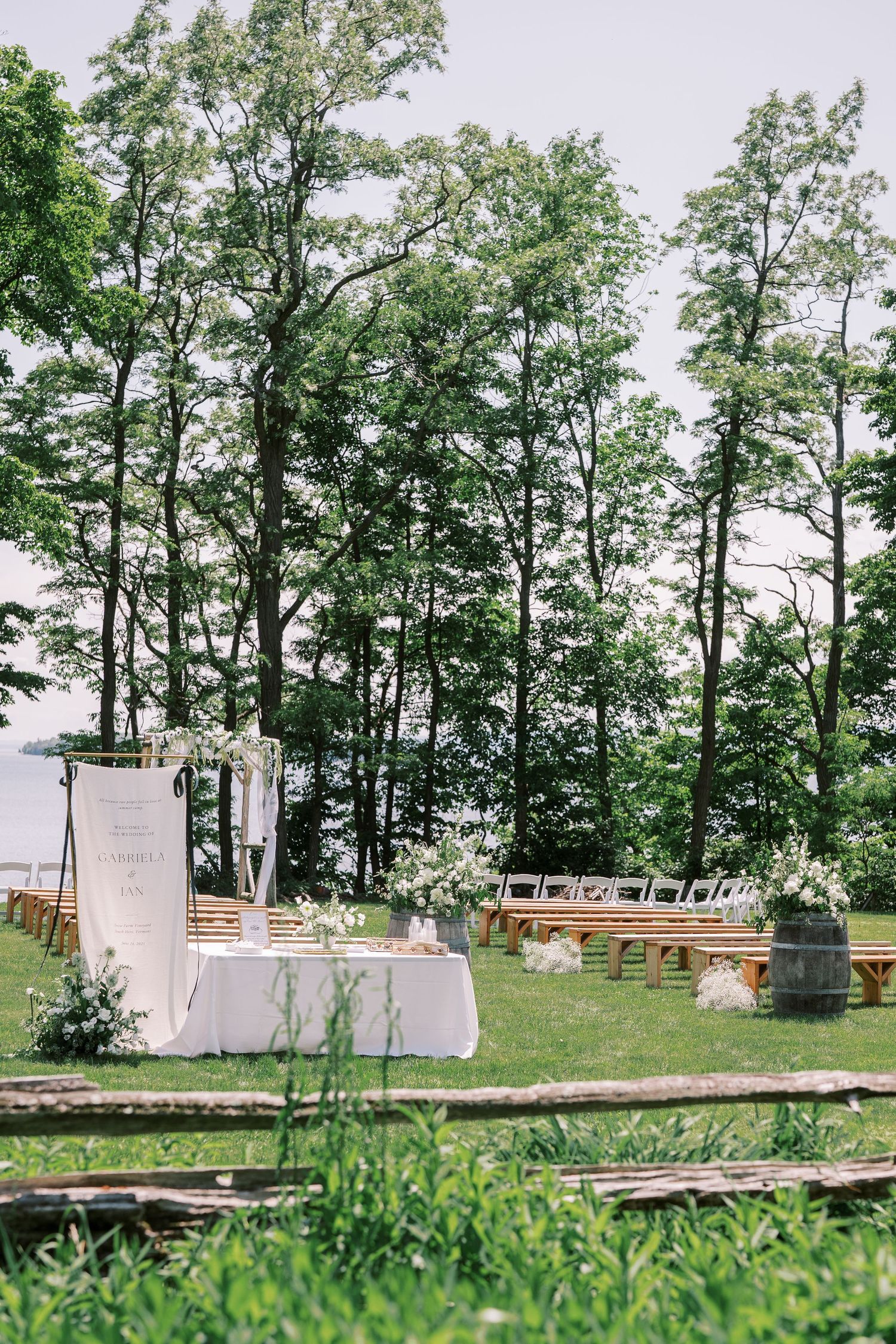 Rustic outdoor wedding ceremony setup with wooden benches and tall trees creating a natural woodland backdrop.