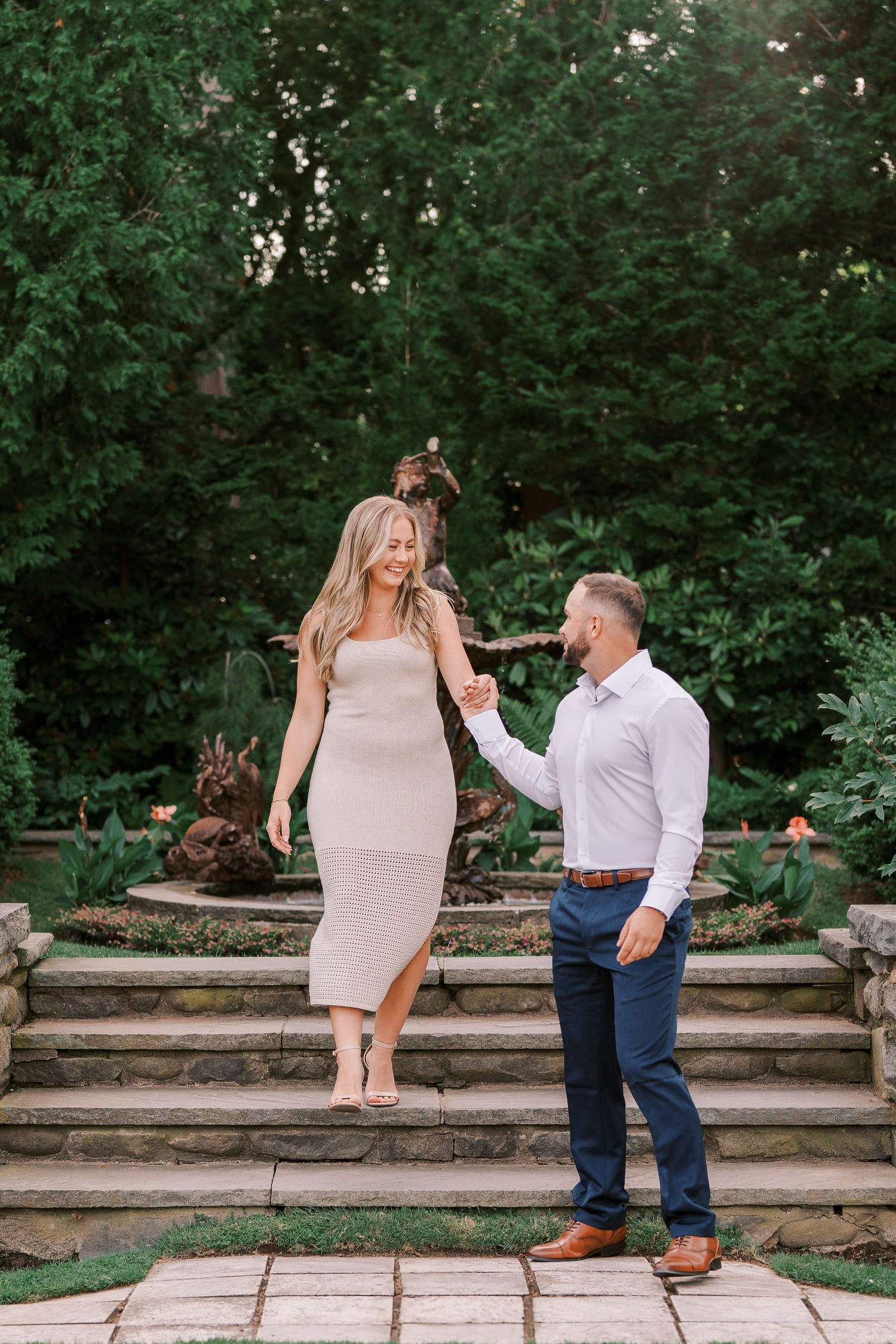 A romantic moment captured on stone garden steps surrounded by lush green foliage.