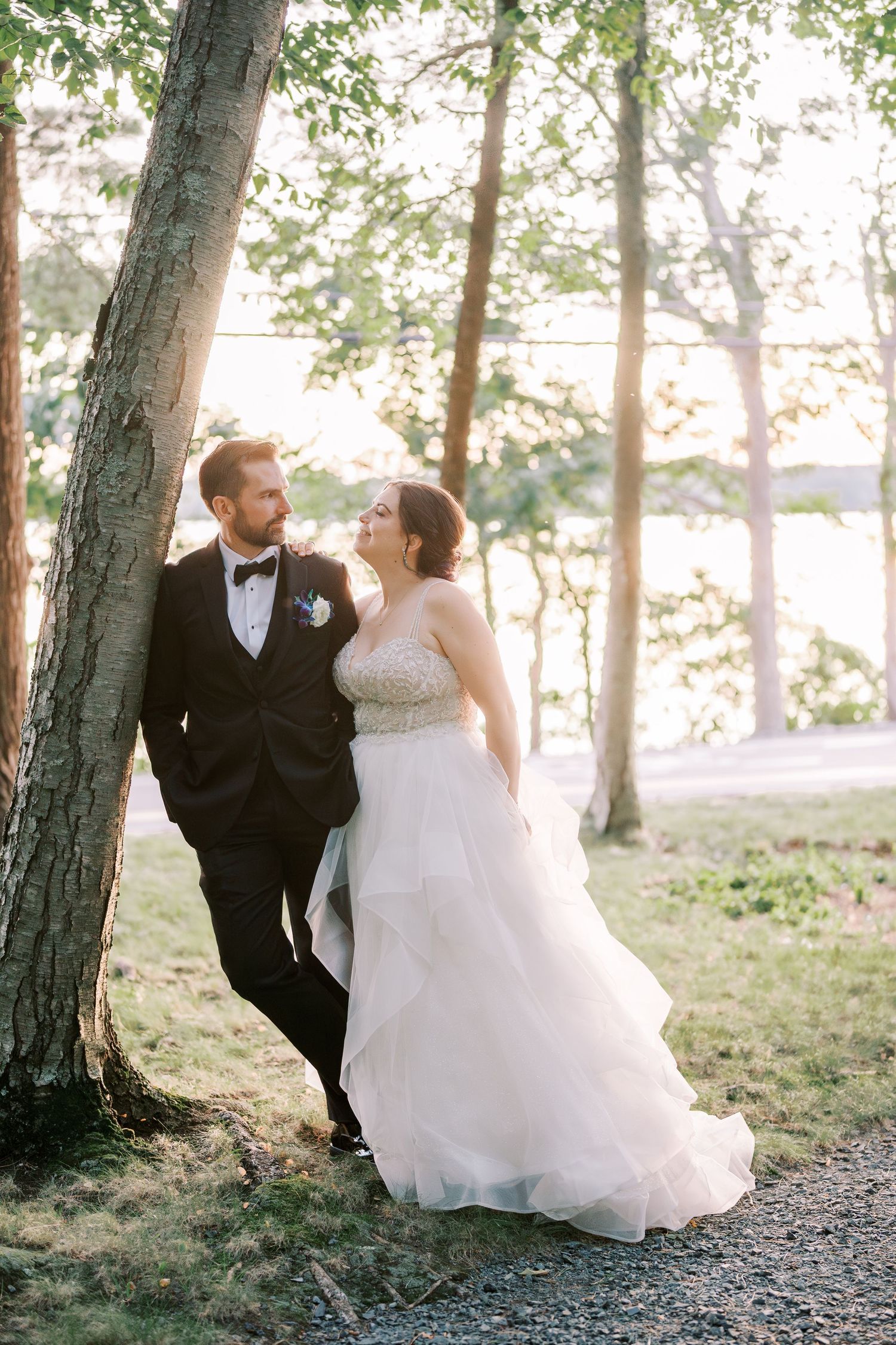 Romantic wedding couple poses in dreamy forest setting at sunset with soft natural lighting through the trees.